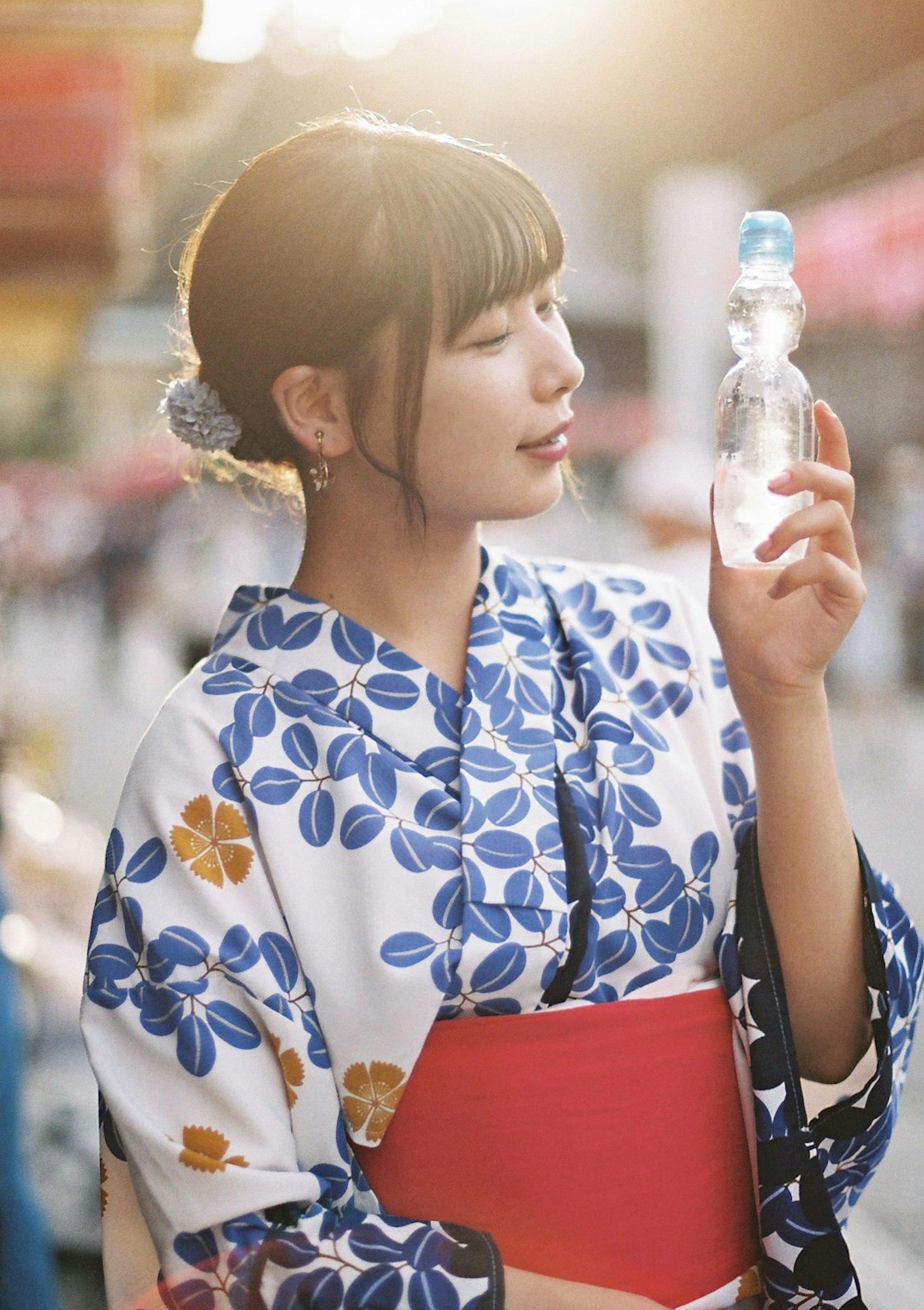 หญิงสาวในกิโมโนลายดอกไม้สีน้ำเงินถือขวดน้ำ