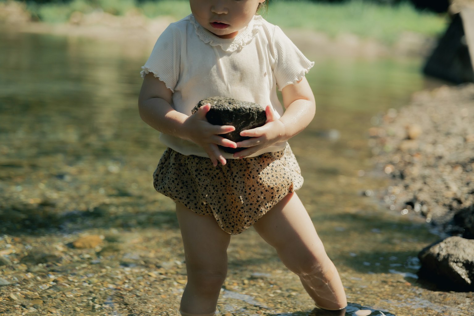 Un bambino che tiene una pietra in acqua bassa
