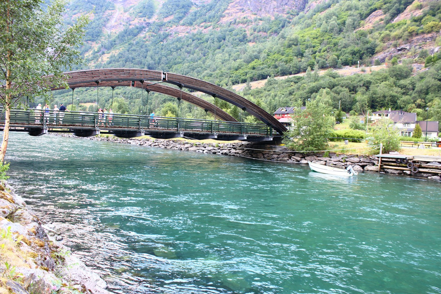 Puente de arco de madera sobre un hermoso río azul rodeado de montañas verdes