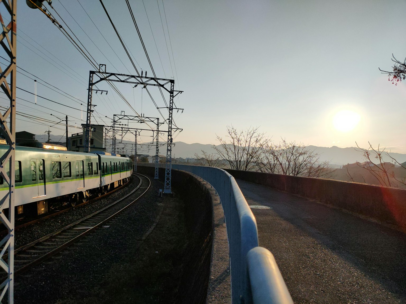 彎曲的鐵道與綠色列車和背景中的日落