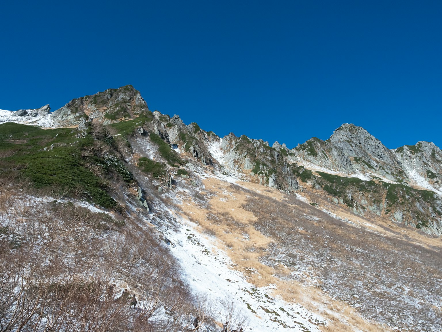 Ladera de montaña con nieve restante y cielo azul claro