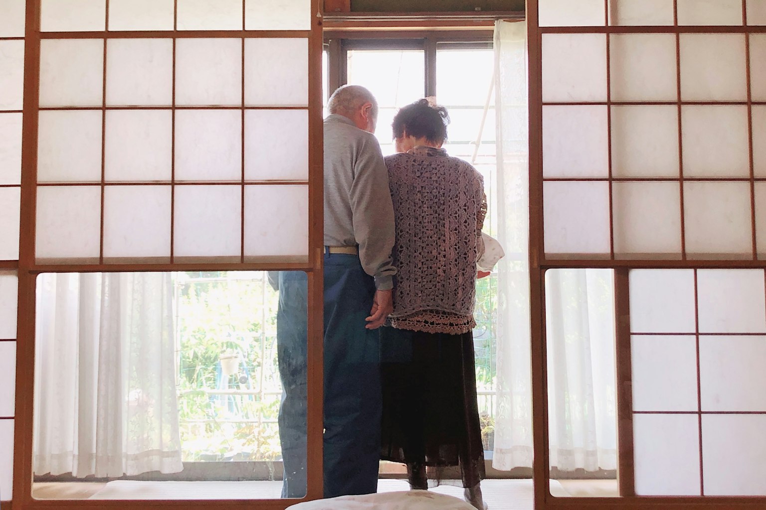 Due anziani che guardano attraverso le porte shoji in una stanza tradizionale giapponese