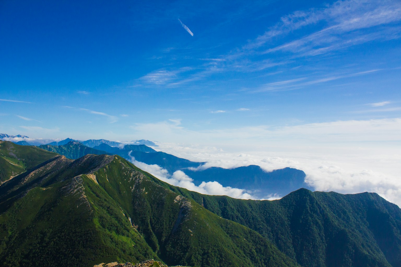 Vaste montagne verdi sotto un cielo blu con nuvole