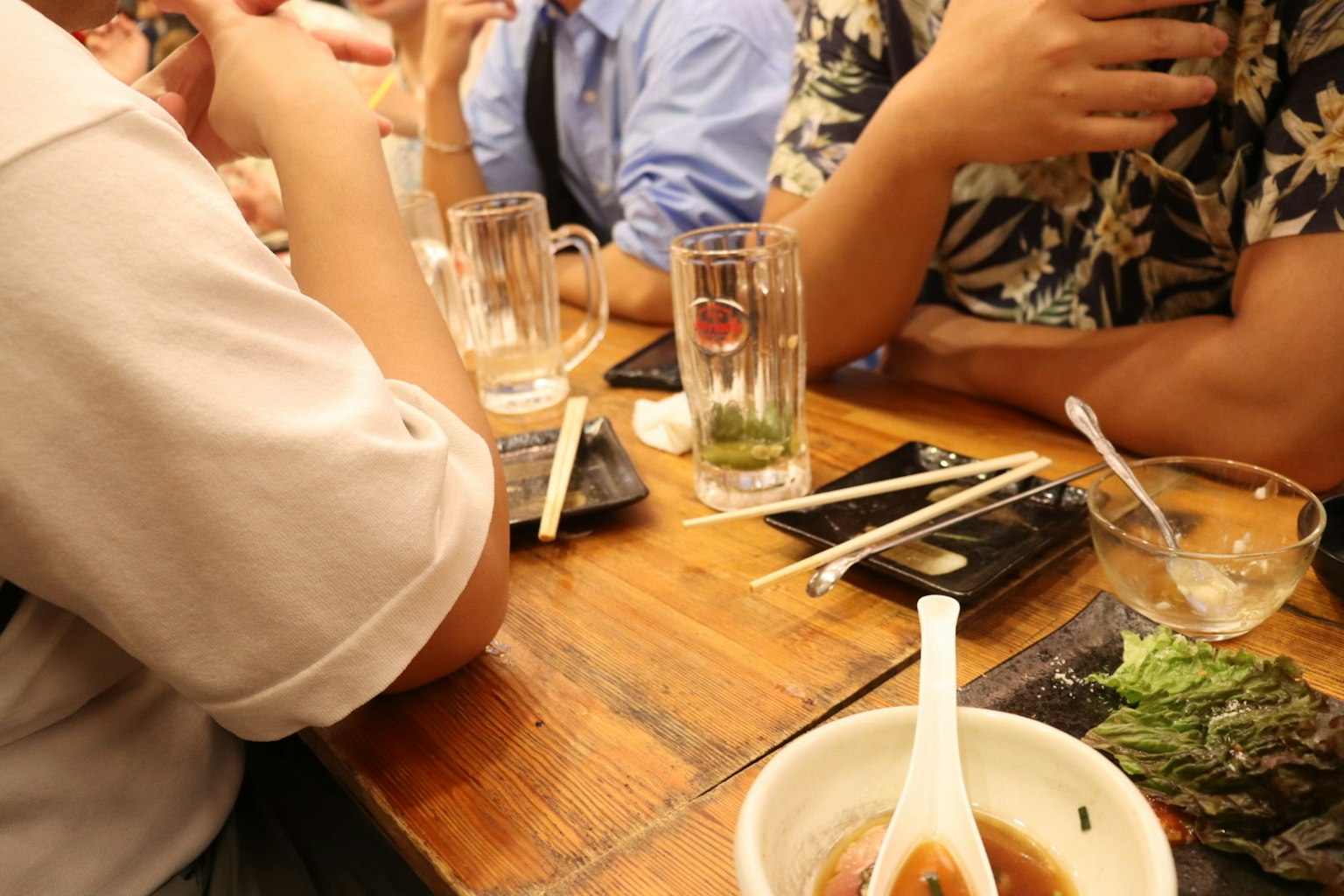 Hands and arms of people around a table with food and drinks
