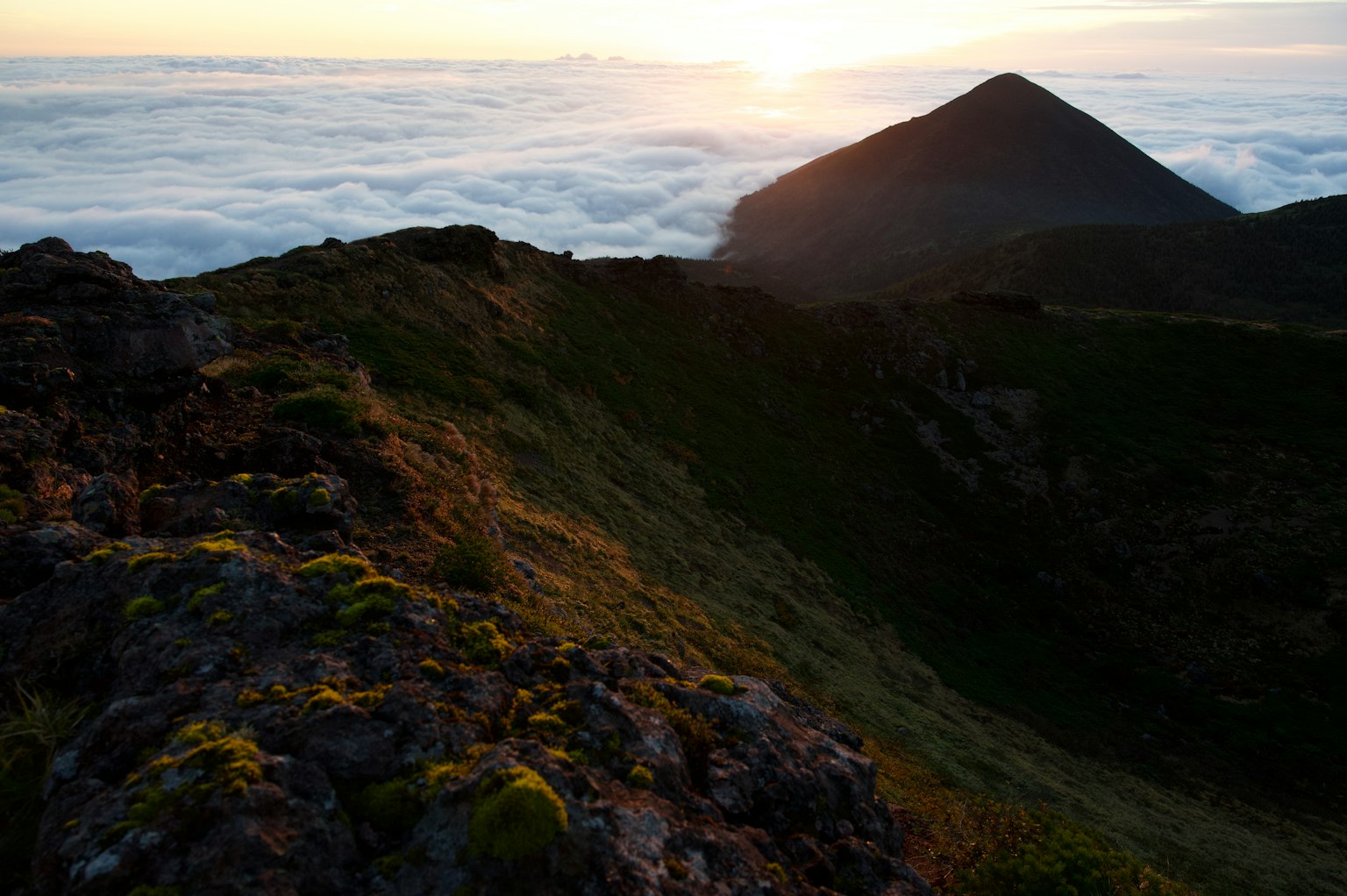Silhouette of a mountain above a sea of clouds with a sunset