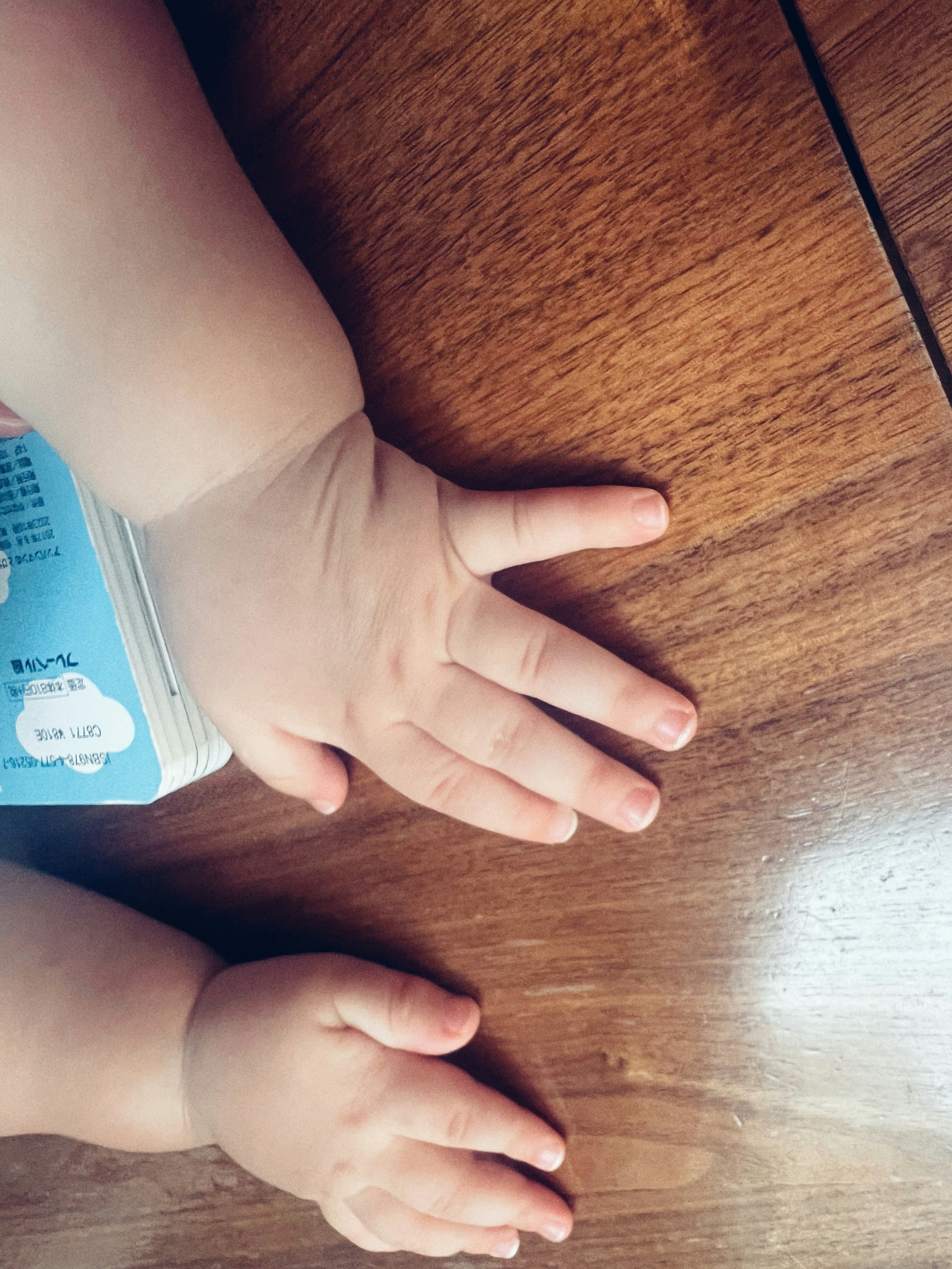 木の床で手をつなぐ親子の手