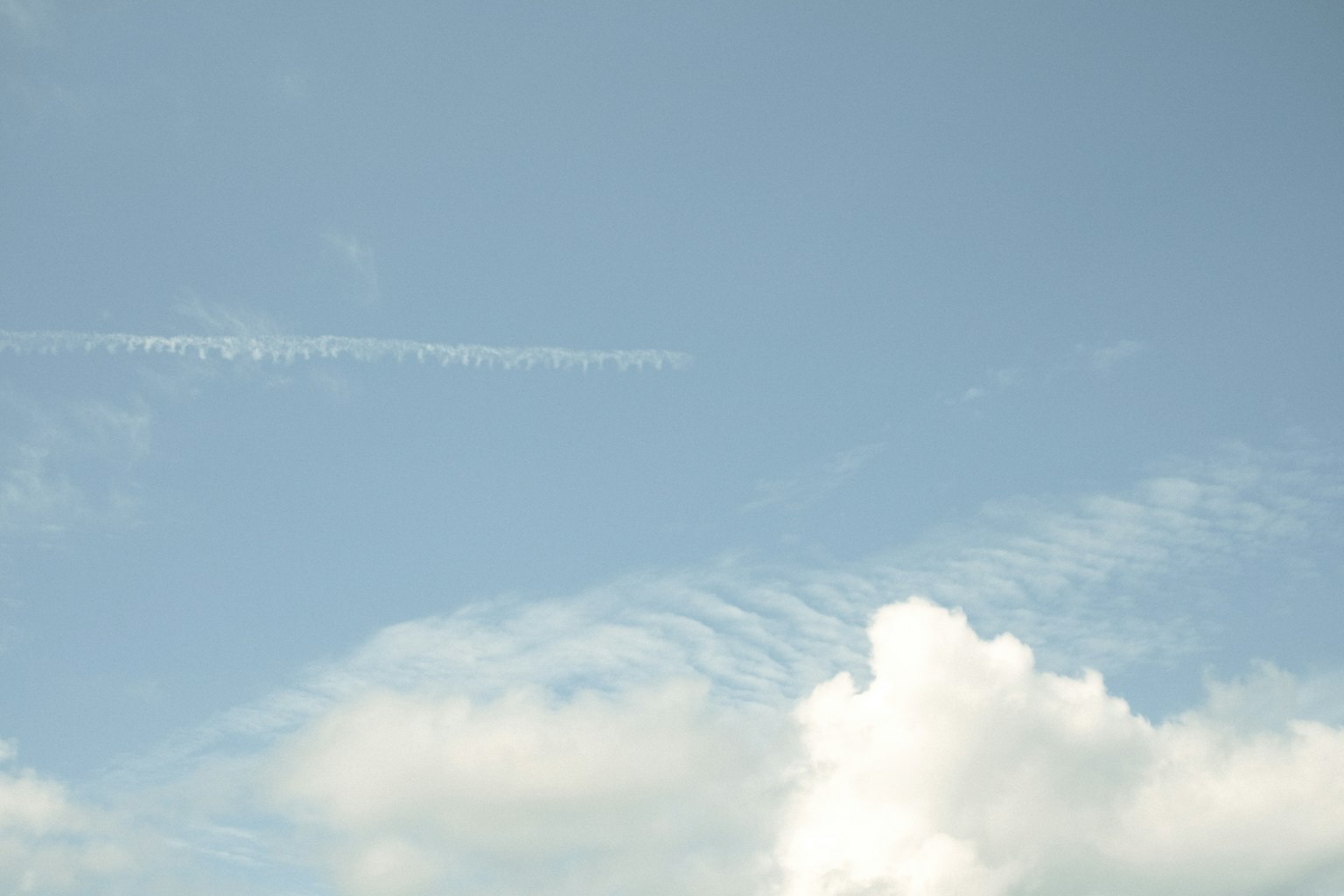 Clear blue sky with white clouds and contrails