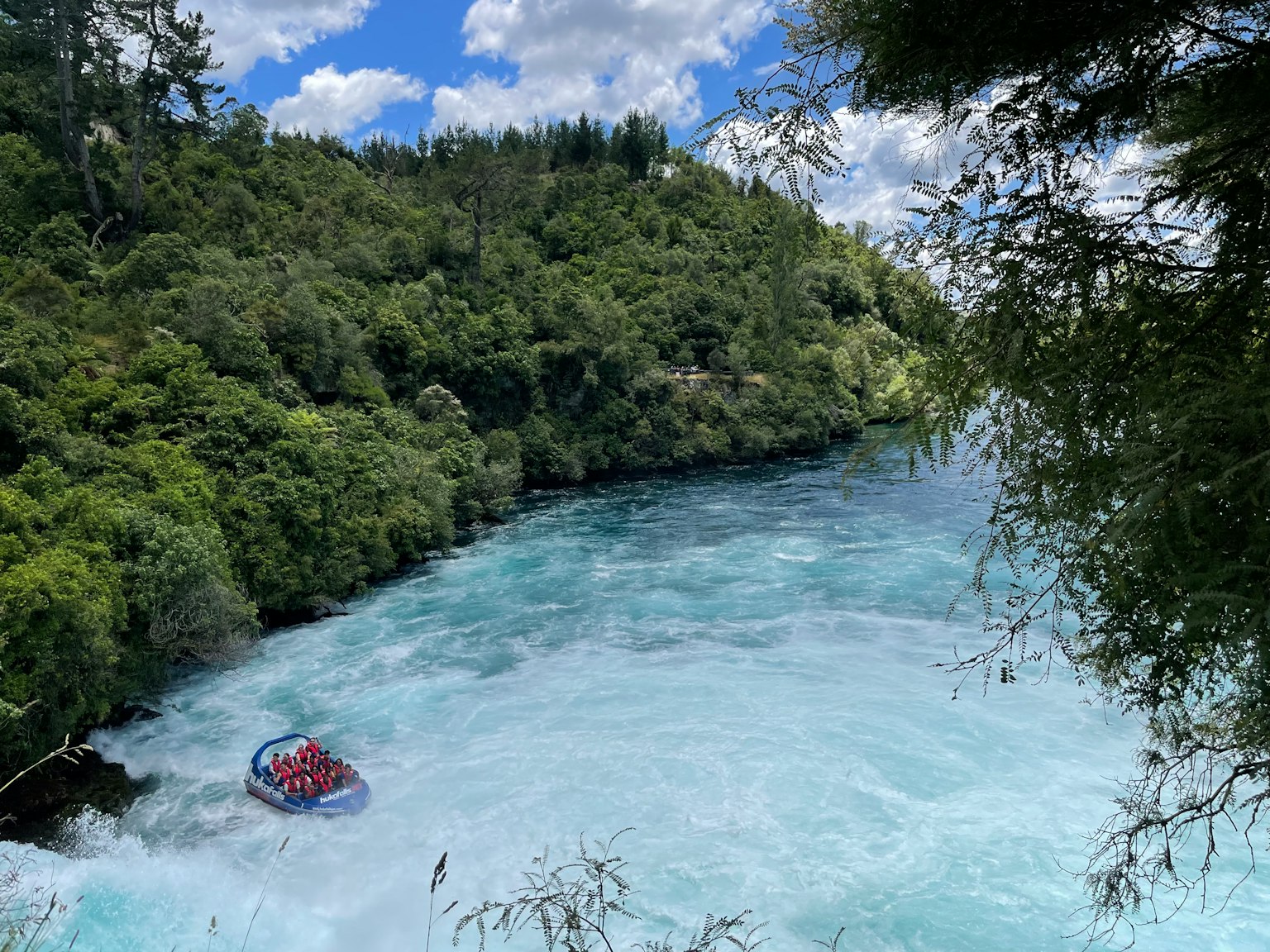 Una barca che naviga in un fiume blu circondato da una foresta verdeggiante