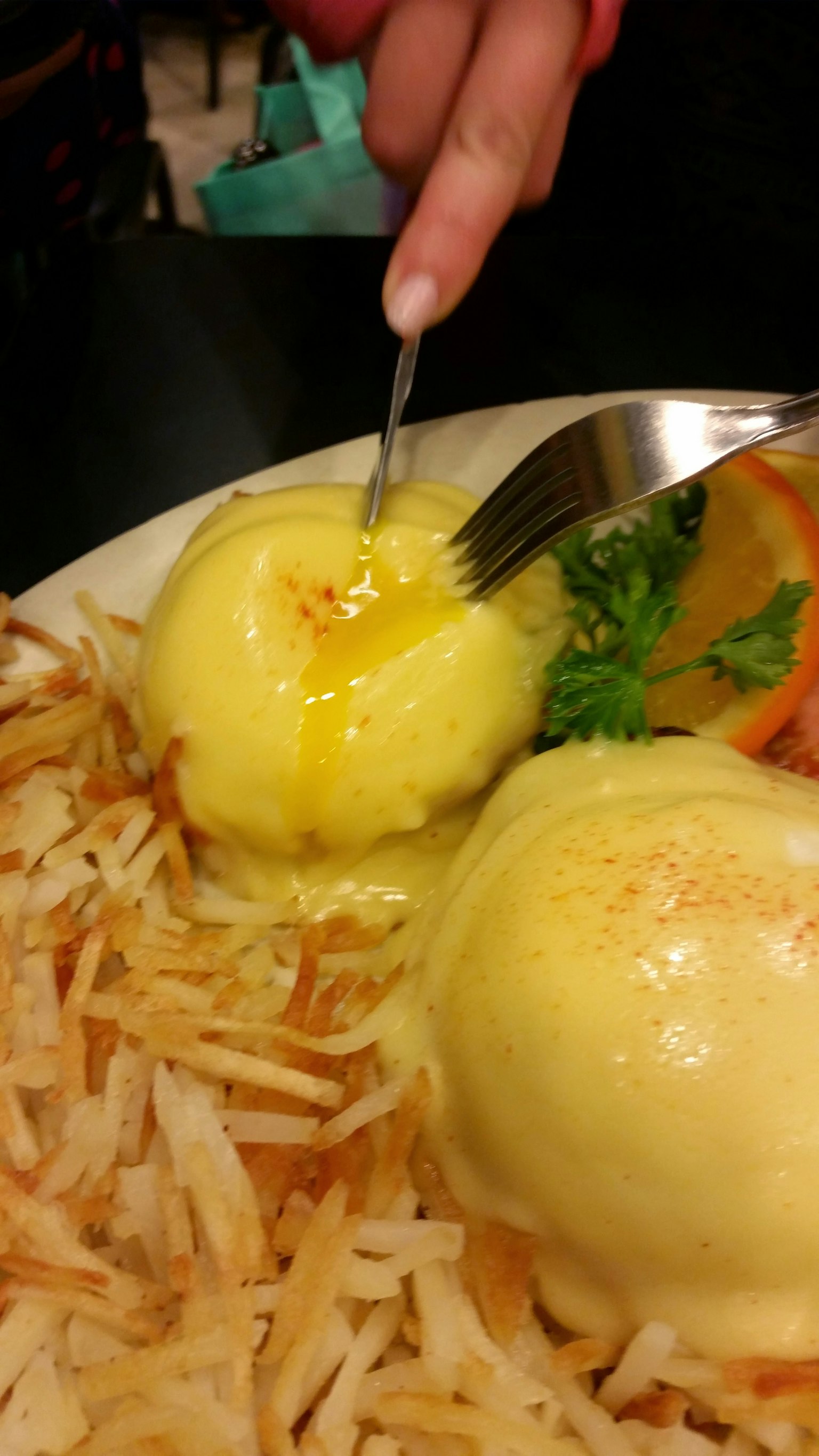 Gros plan sur des œufs coulants coupés avec une fourchette sur une assiette de pommes de terre rissolées