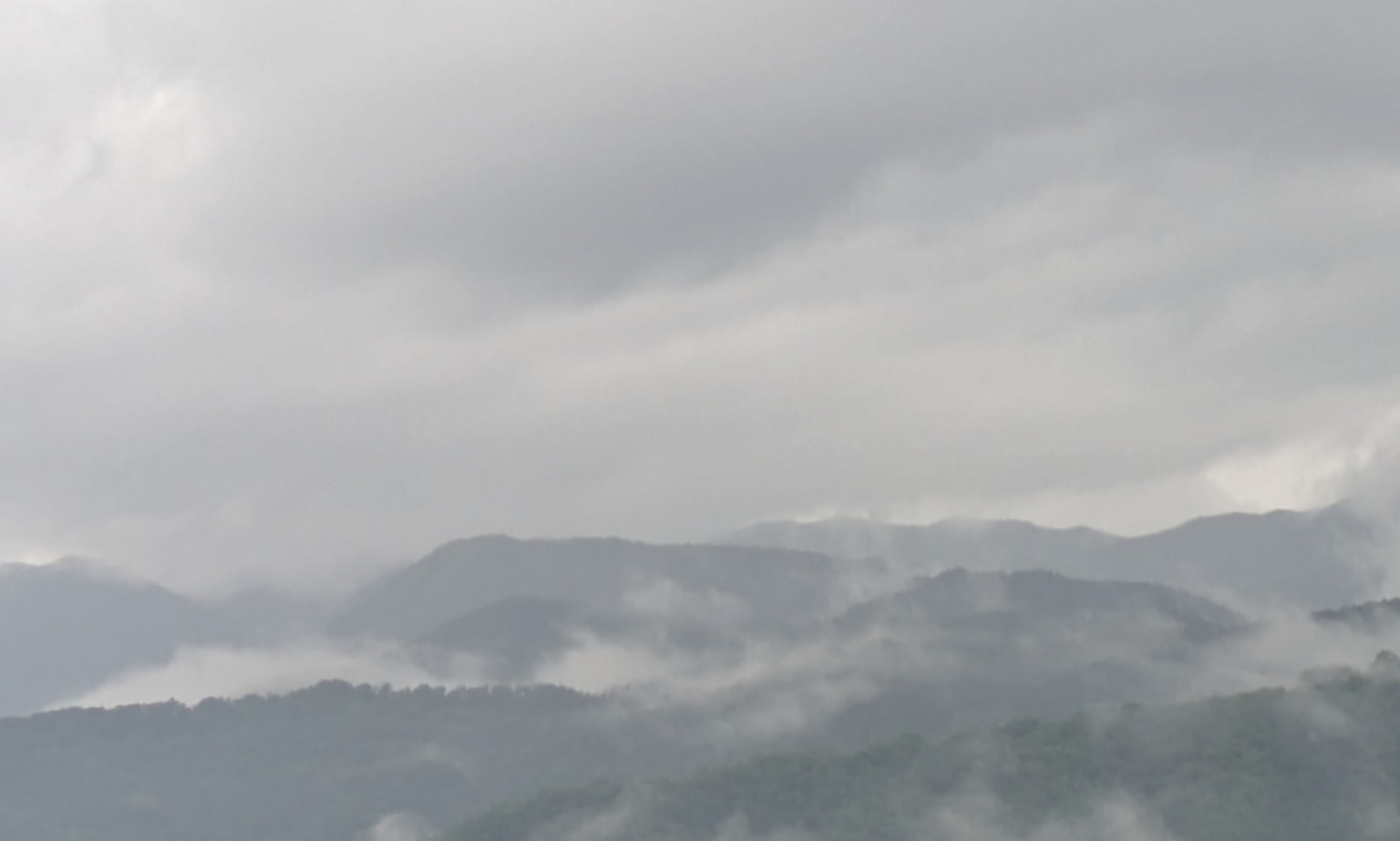 霧に包まれた山々と曇り空の風景