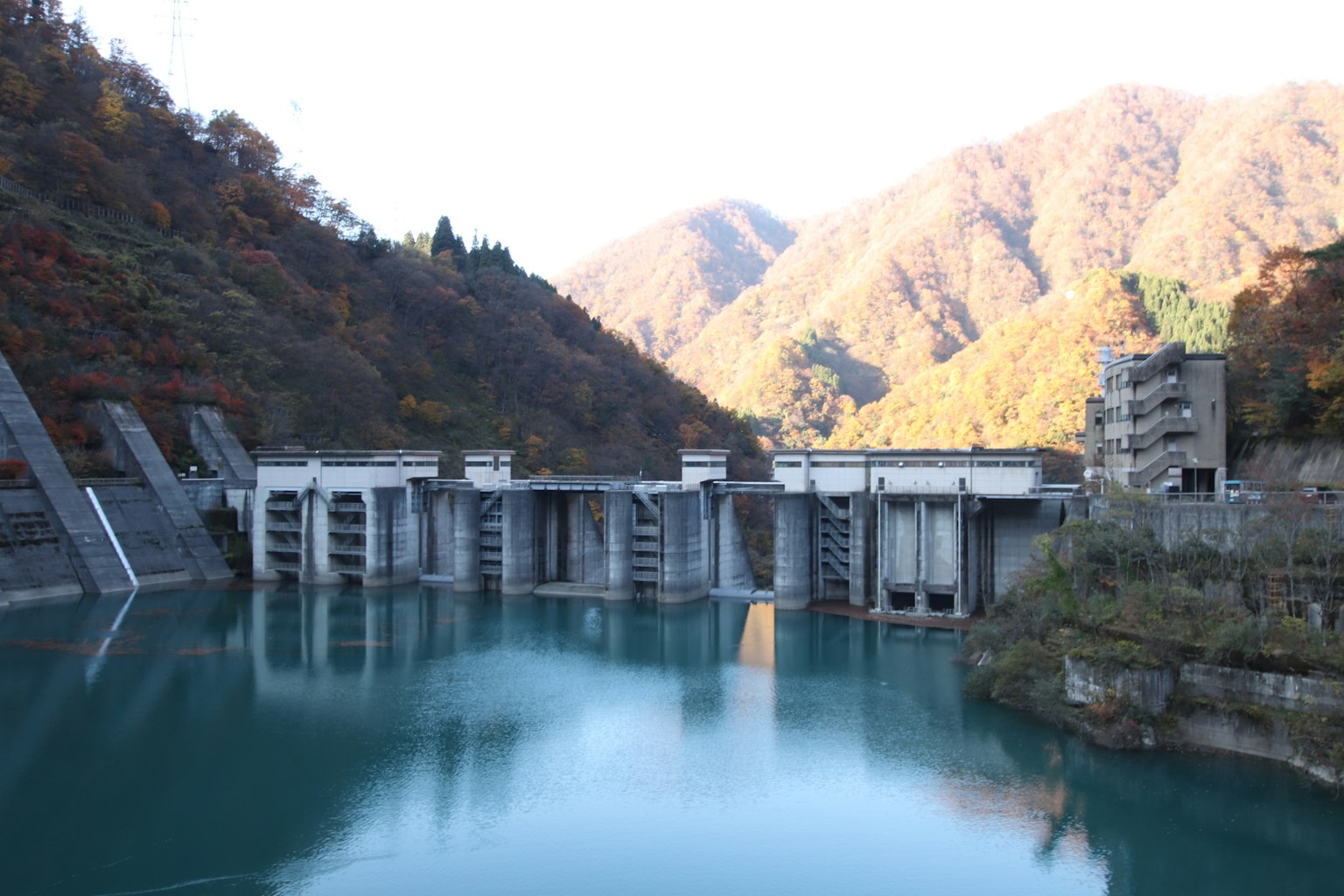 ทิวทัศน์ของเขื่อนที่มีภูเขาล้อมรอบและทะเลสาบที่สงบ
