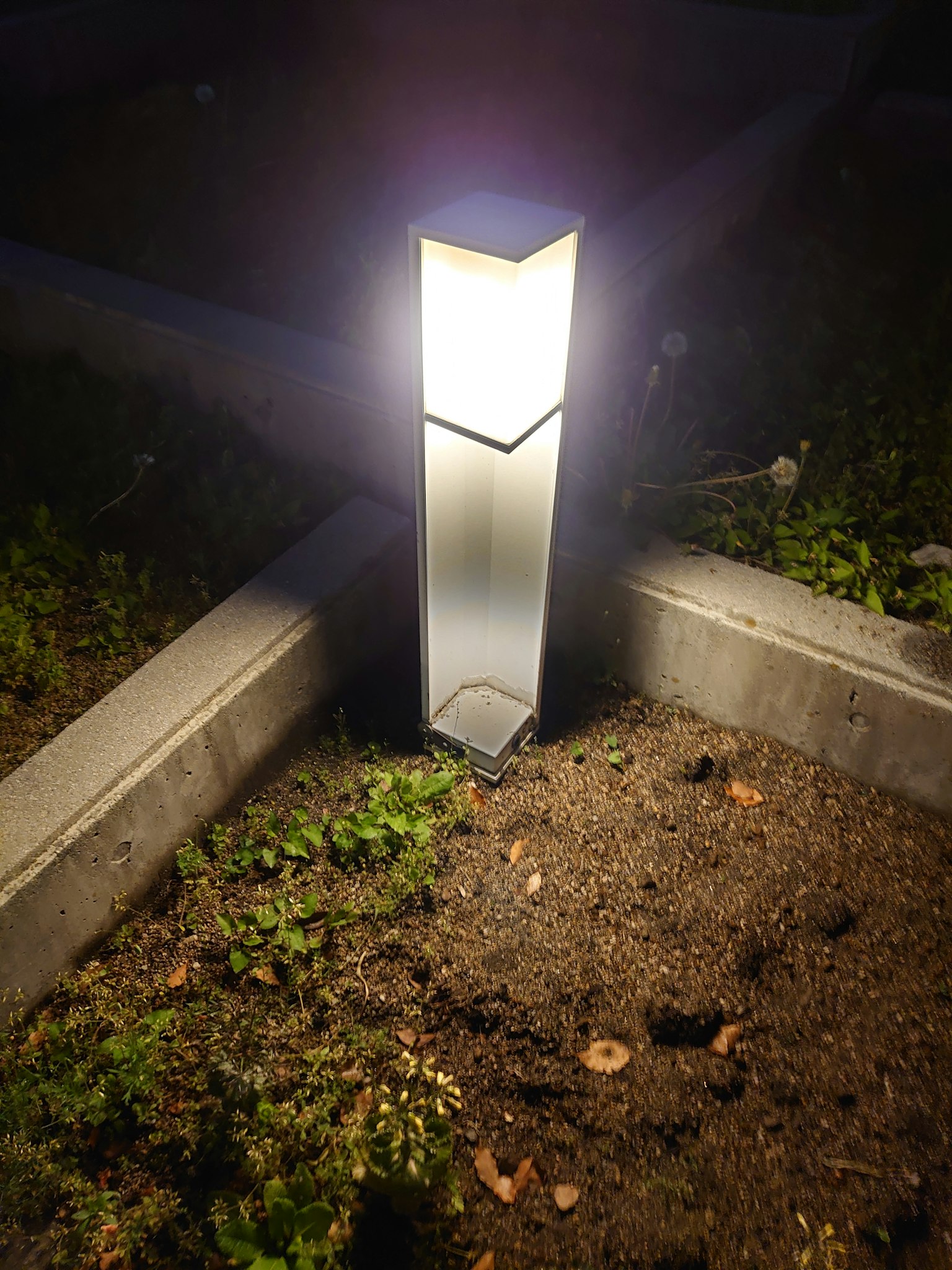 Moderne Gartenlampe leuchtet nachts auf dem Boden