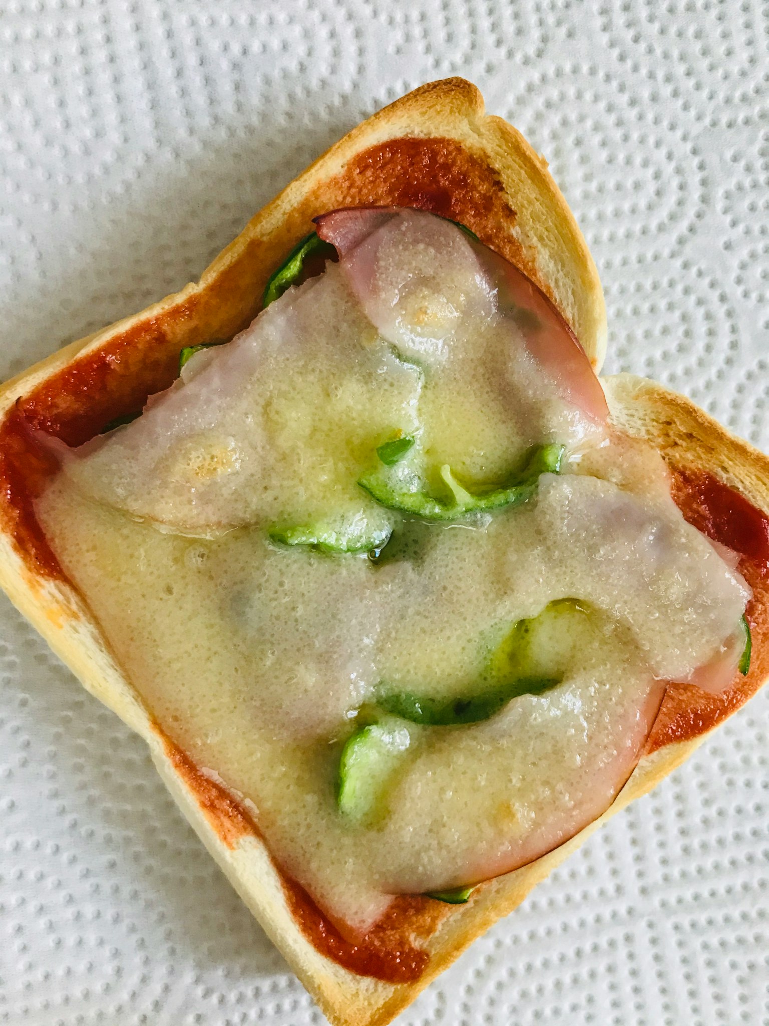 烤面包上铺有火腿和青椒，覆盖融化的奶酪
