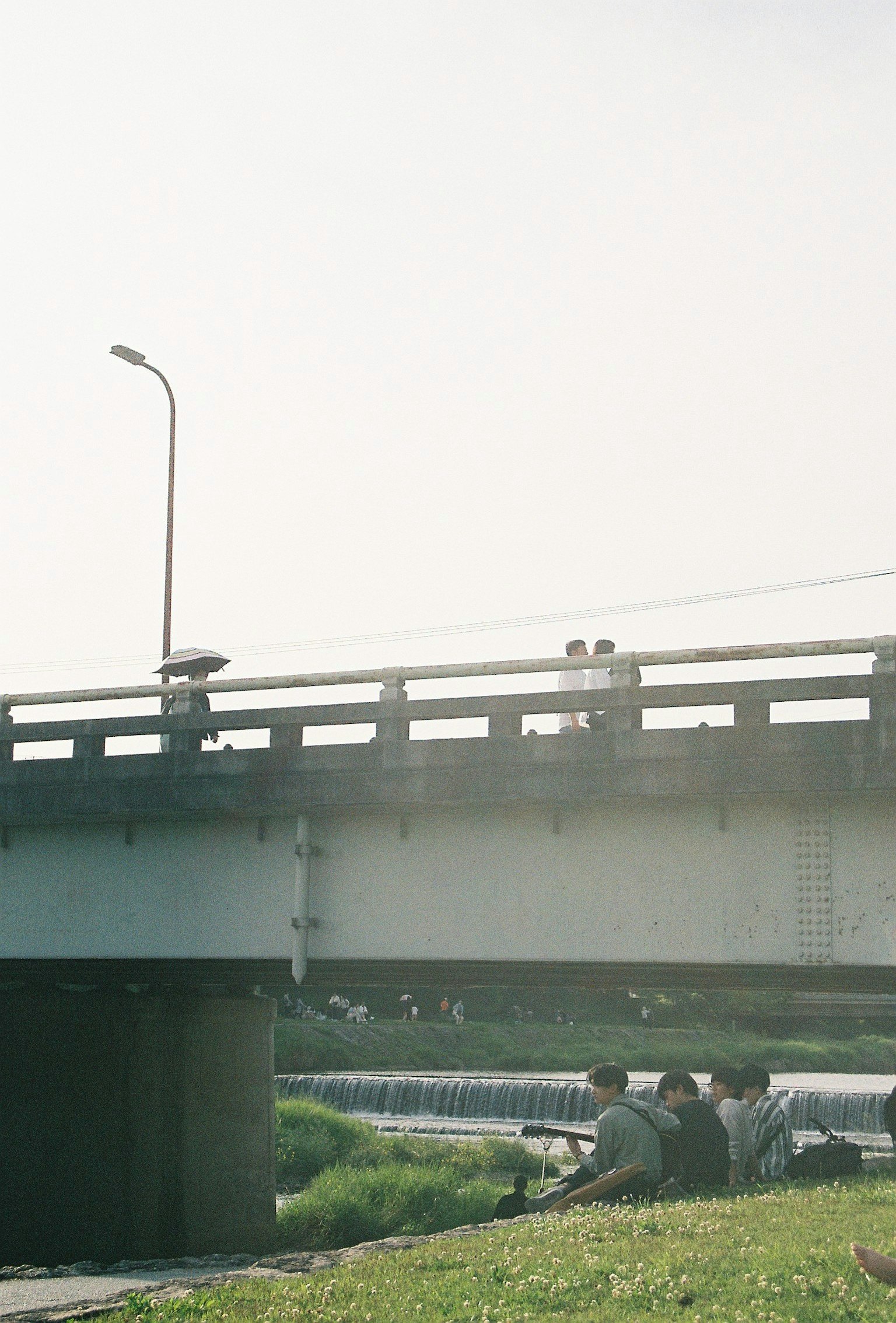 People relaxing under a bridge with a riverside view