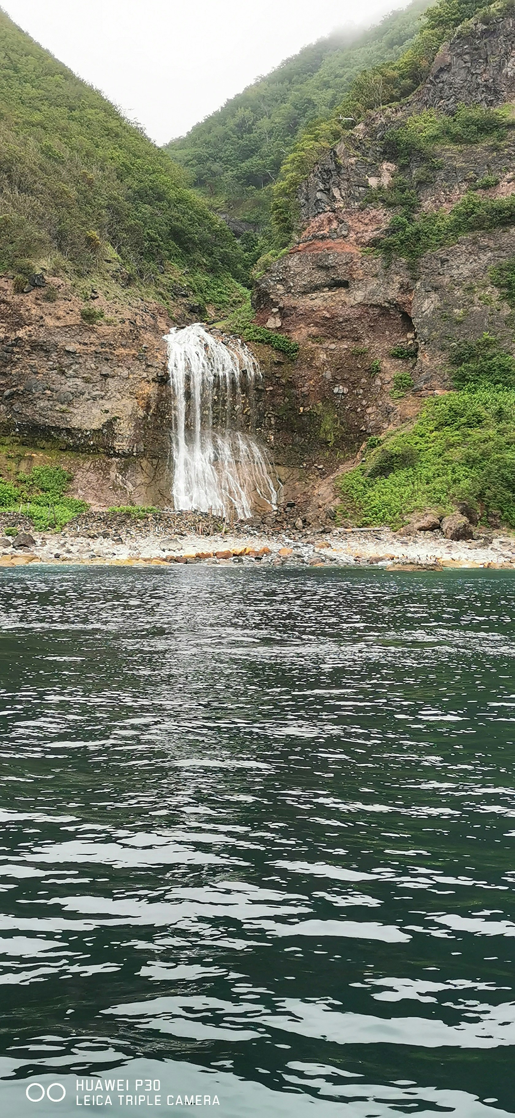 渓谷の岩肌から流れ落ちる小さな滝と湖面の水しぶき