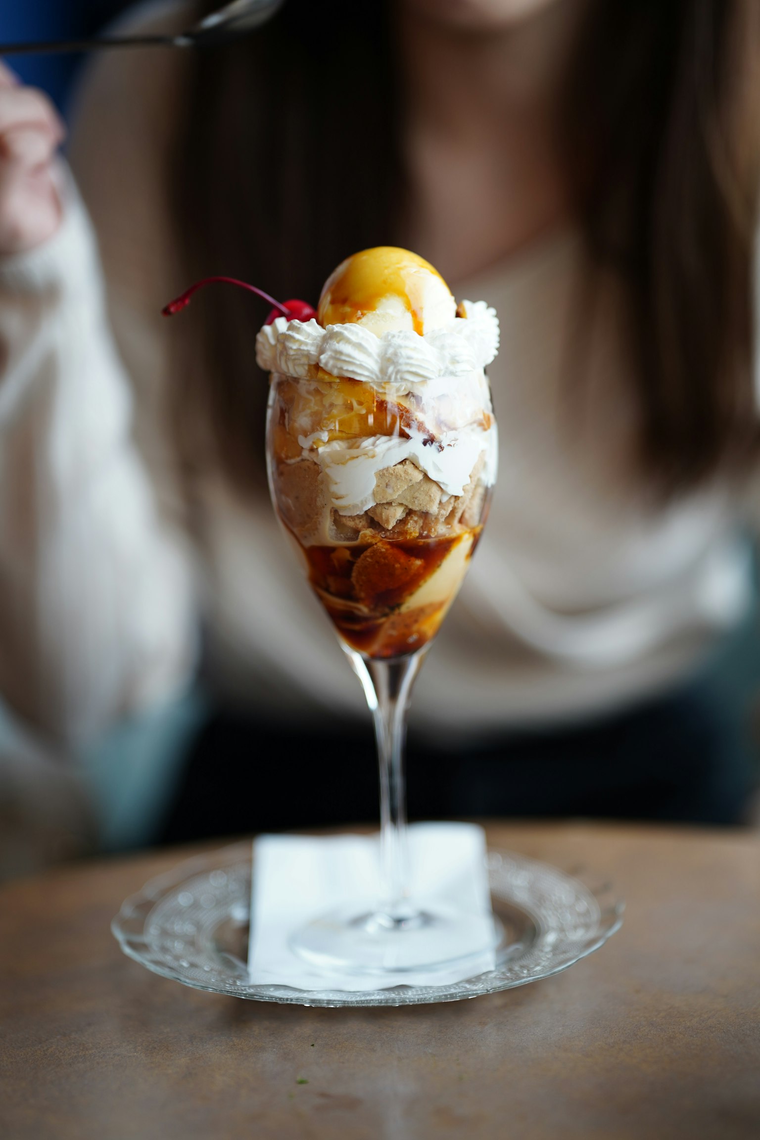 Un bellissimo parfait di gelato servito in un bicchiere con sopra un'arancia e panna montata