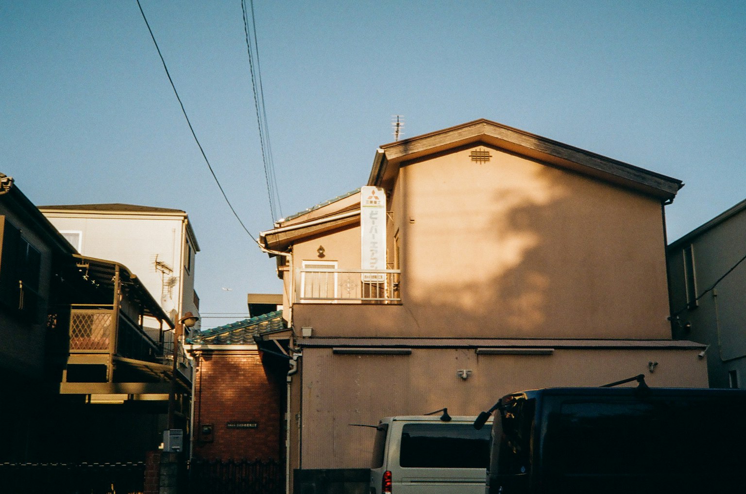 A light-colored house in a residential area with a clear blue sky