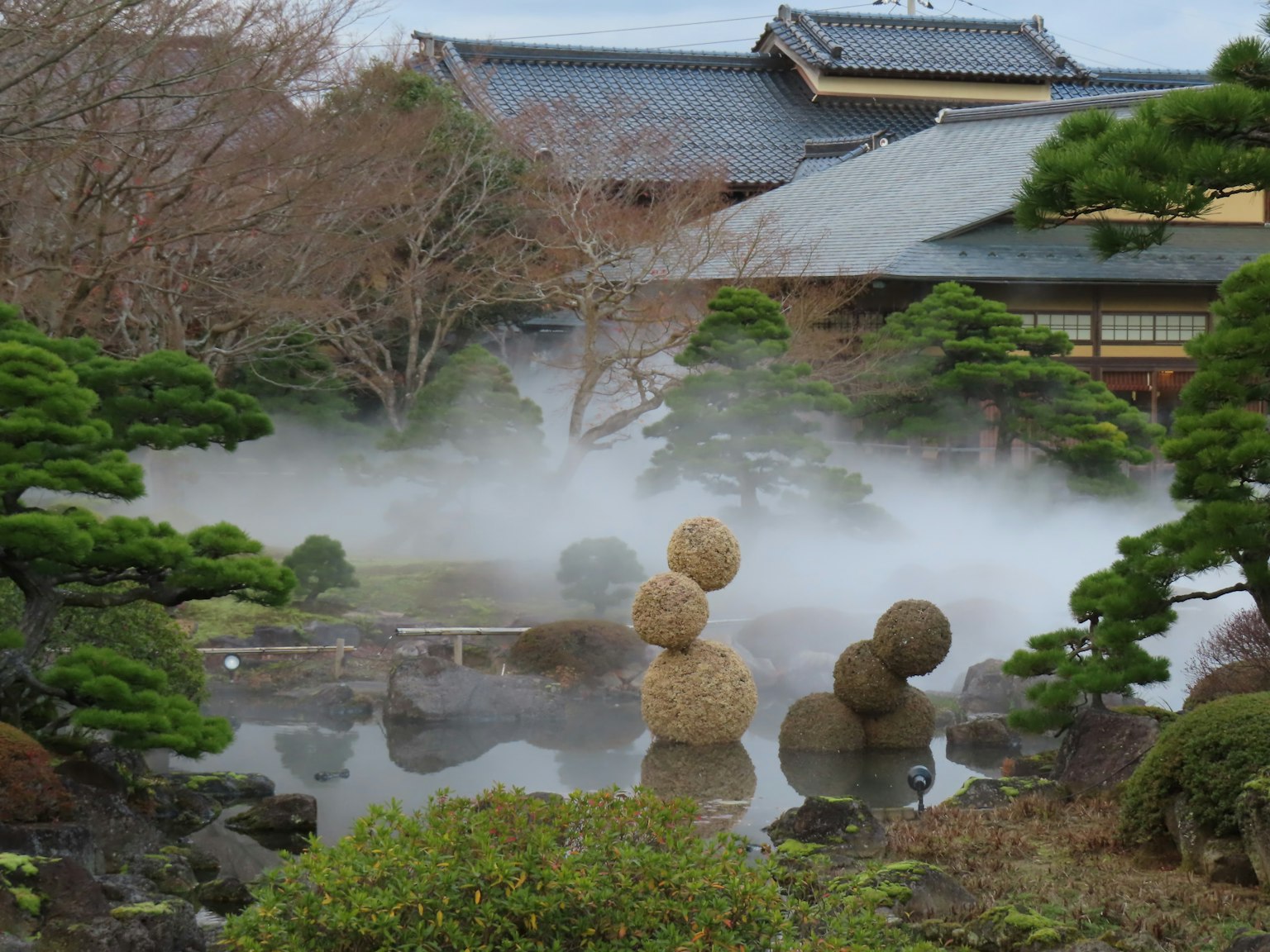 Japanischer Garten mit Nebel und ornamentalen Strohkugeln in einem Teich