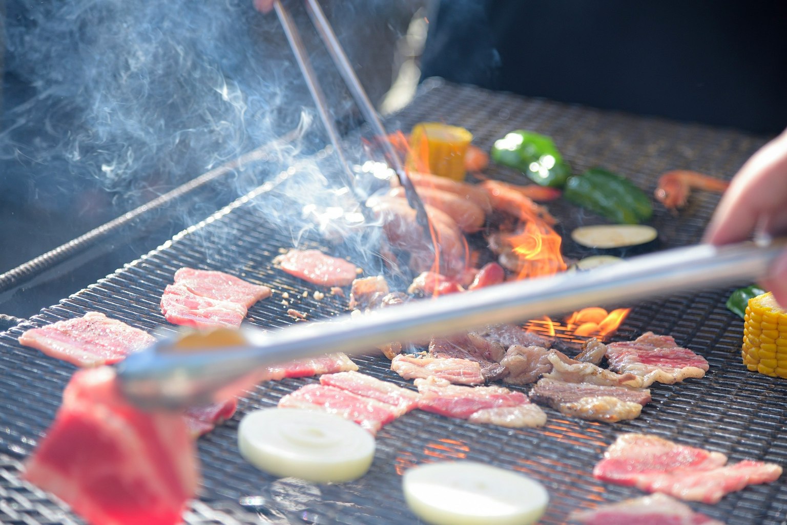 Grilling meat and vegetables on a barbecue with smoke
