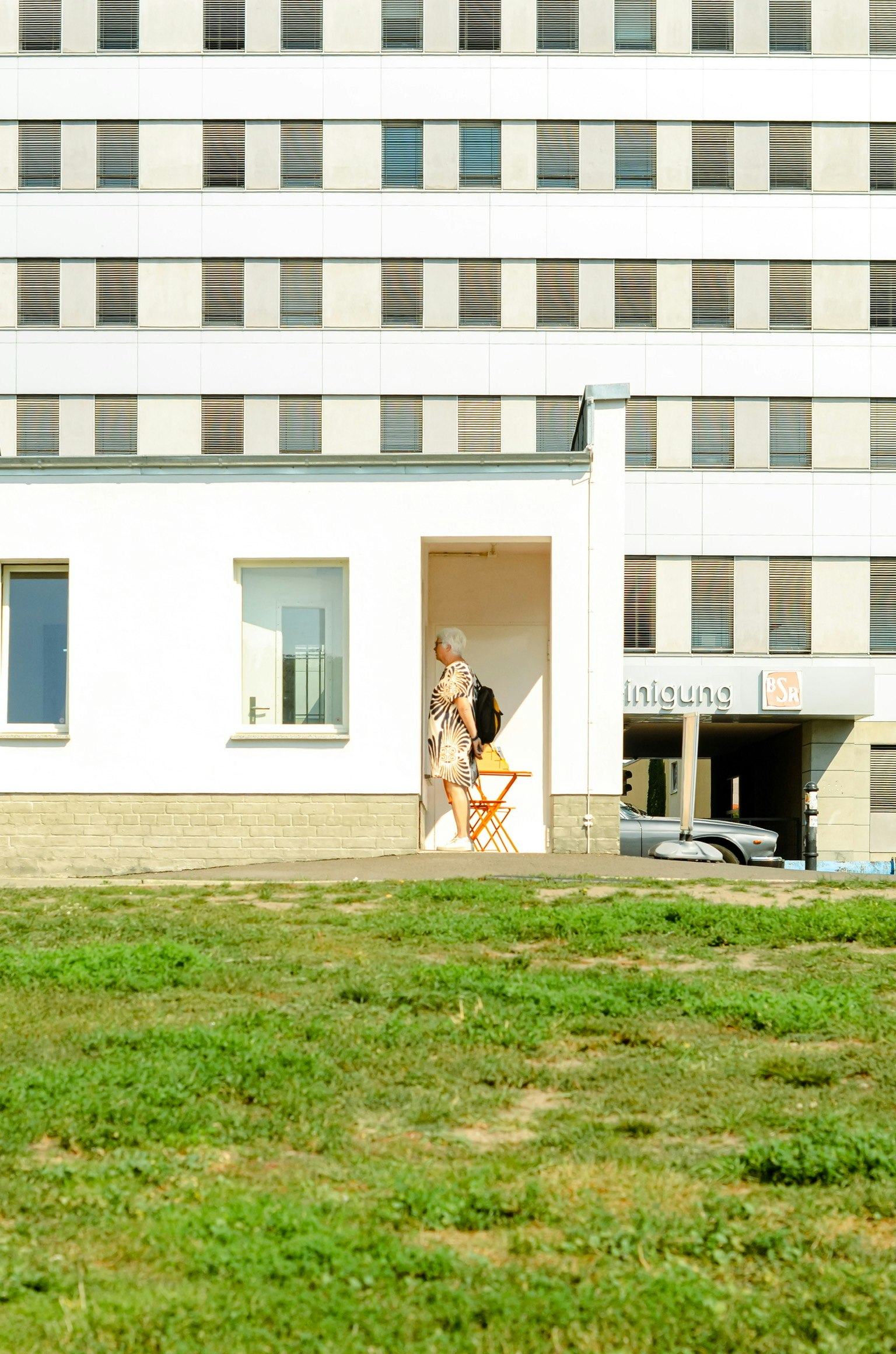 白い建物の前に立つ人物 緑の草地と現代的な建築