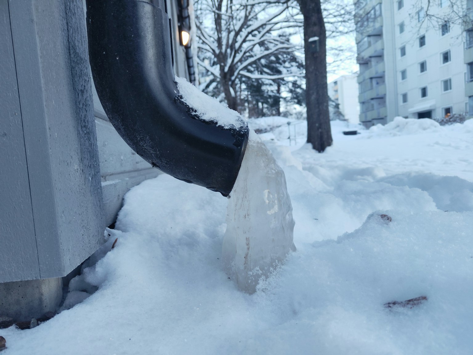 冰柱在排水管末端形成，周圍被雪覆蓋