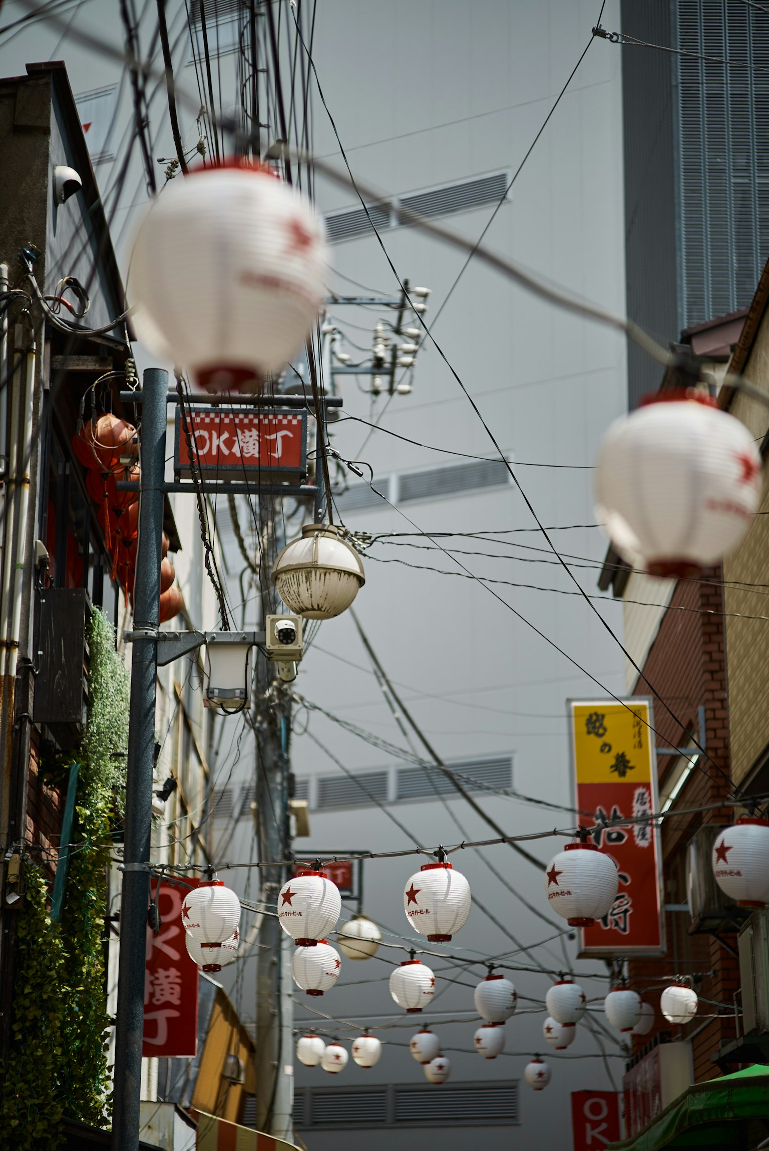 Callejón estrecho adornado con faroles rojos líneas eléctricas y edificios al fondo