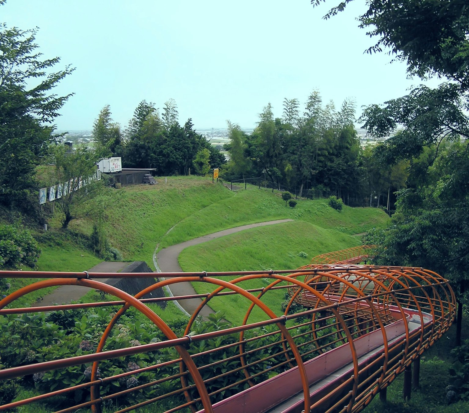ทิวทัศน์ที่สวยงามของสวนสีเขียวพร้อมสะพานรูปอุโมงค์สีส้ม