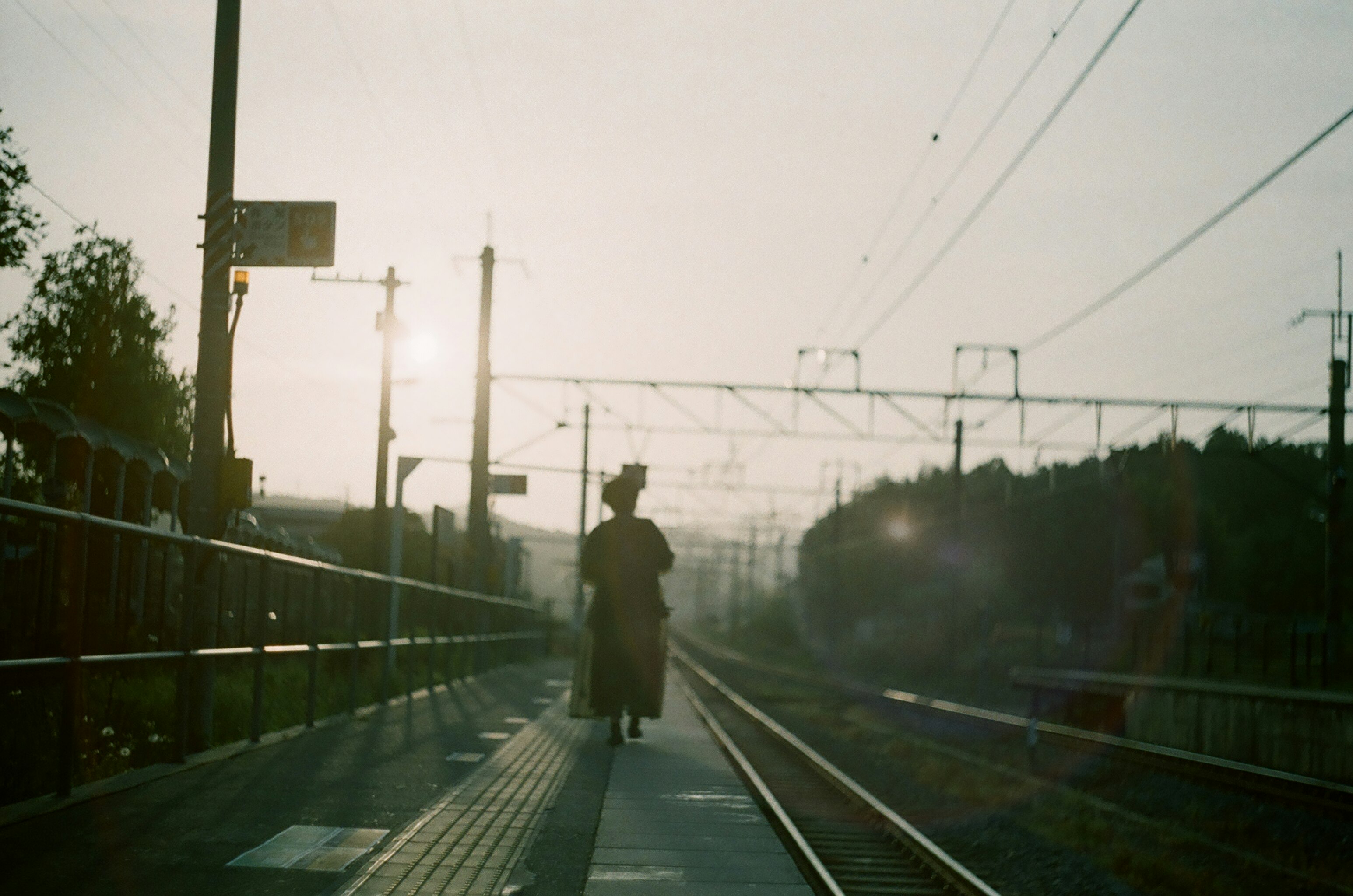 eine einzelne Person, die bei Dämmerung entlang der Bahngleise geht