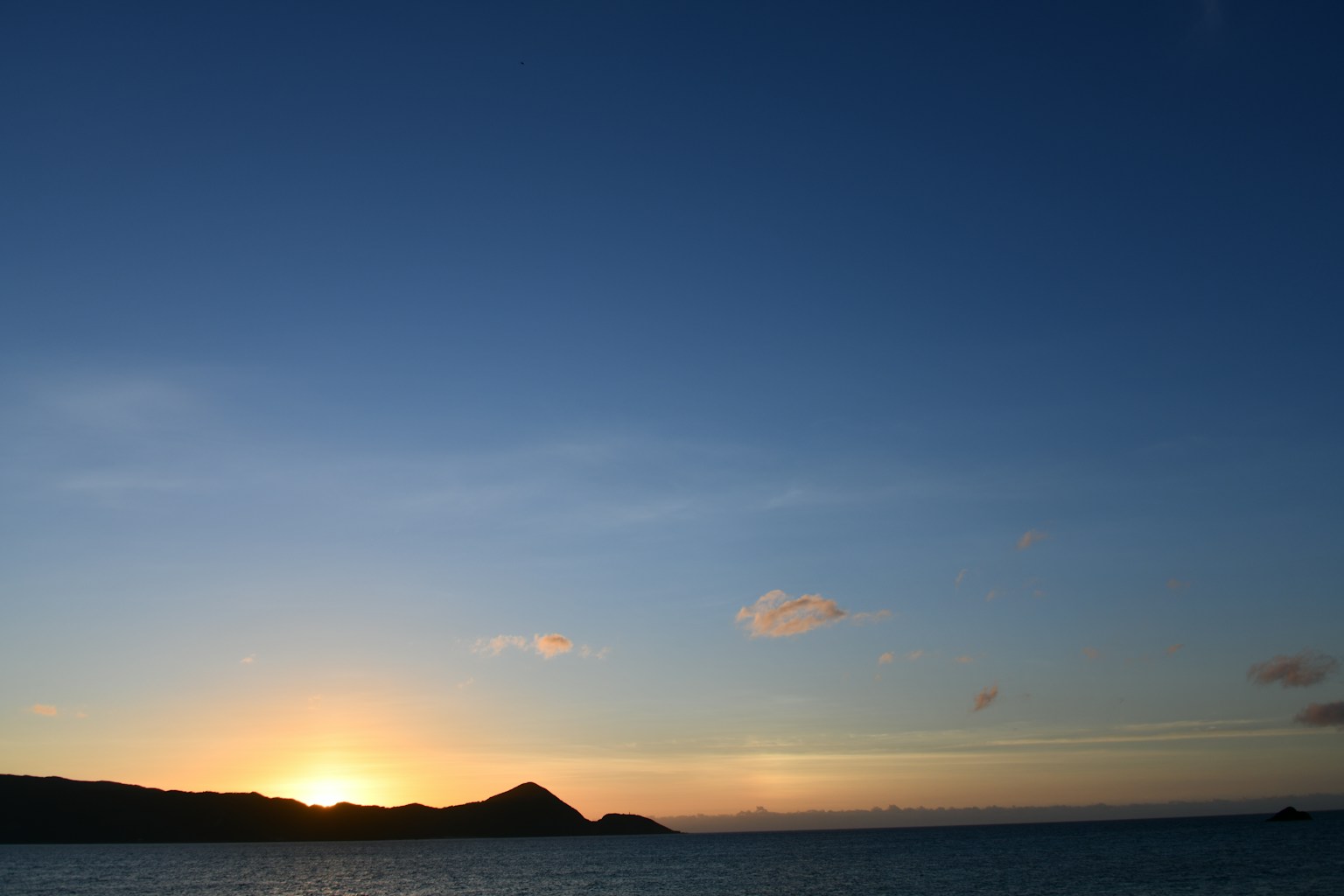 Sunset over the ocean with a silhouette of a distant island