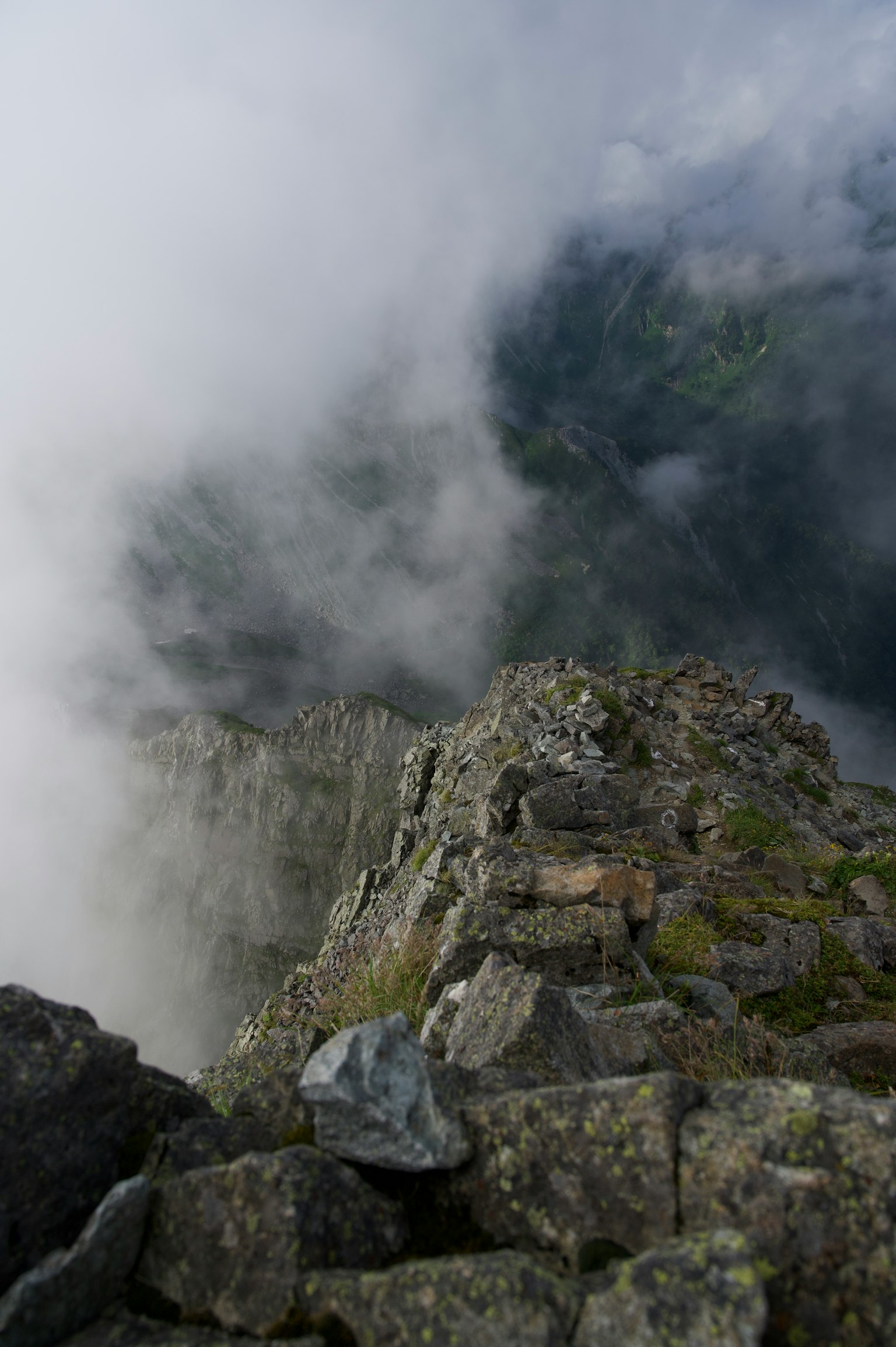 Berggipfel in Nebel gehüllt mit steinigem Weg und tiefem Tal