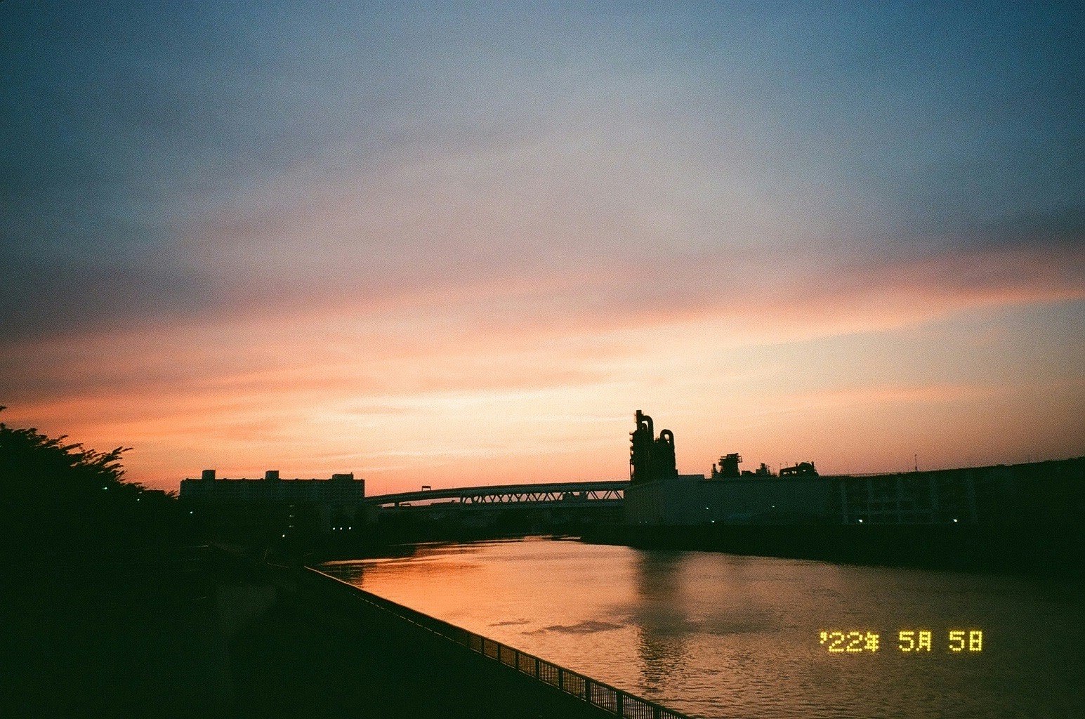夕焼けの川沿いを走る橋と遊歩道の風景