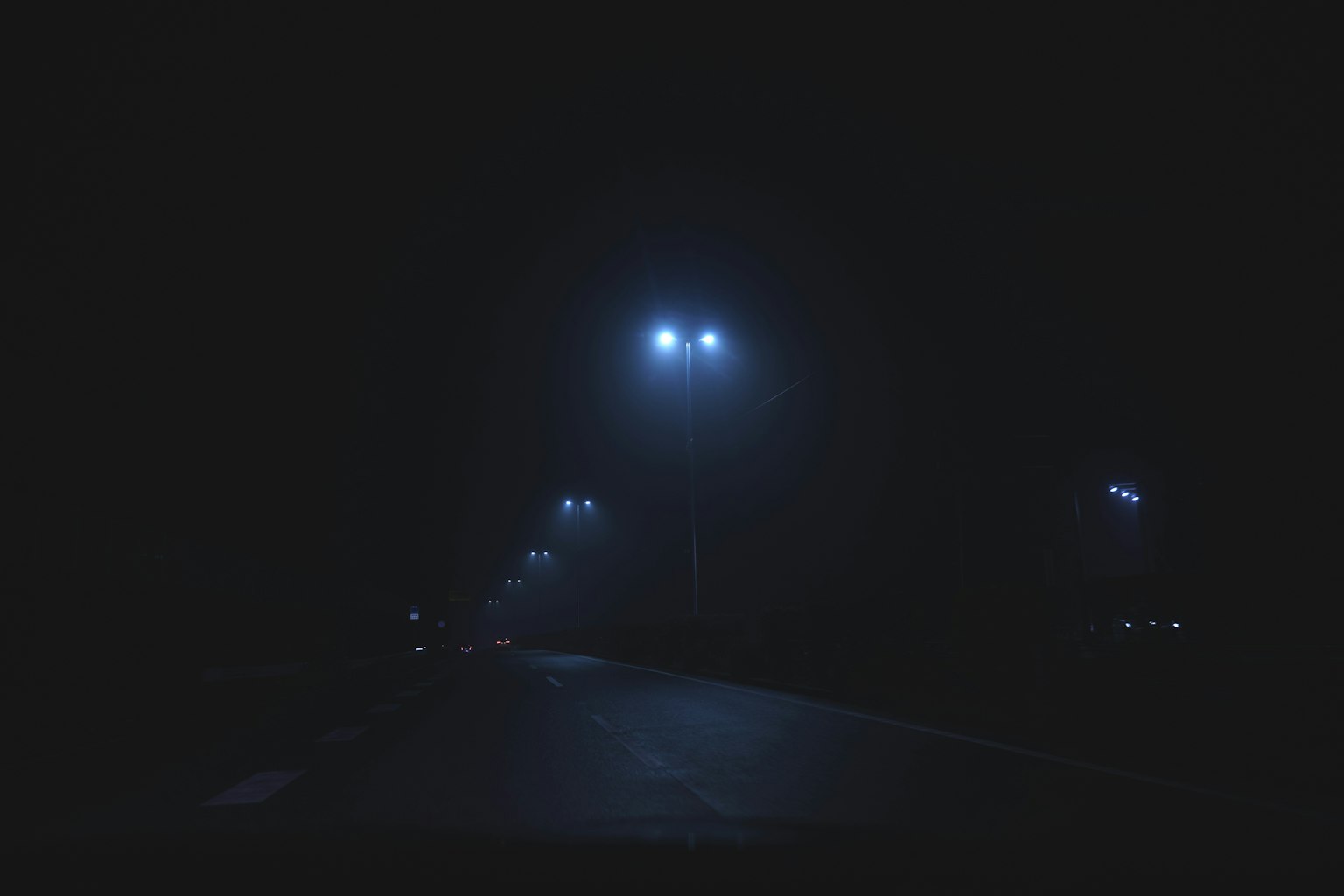 Una strada buia illuminata da lampioni blu