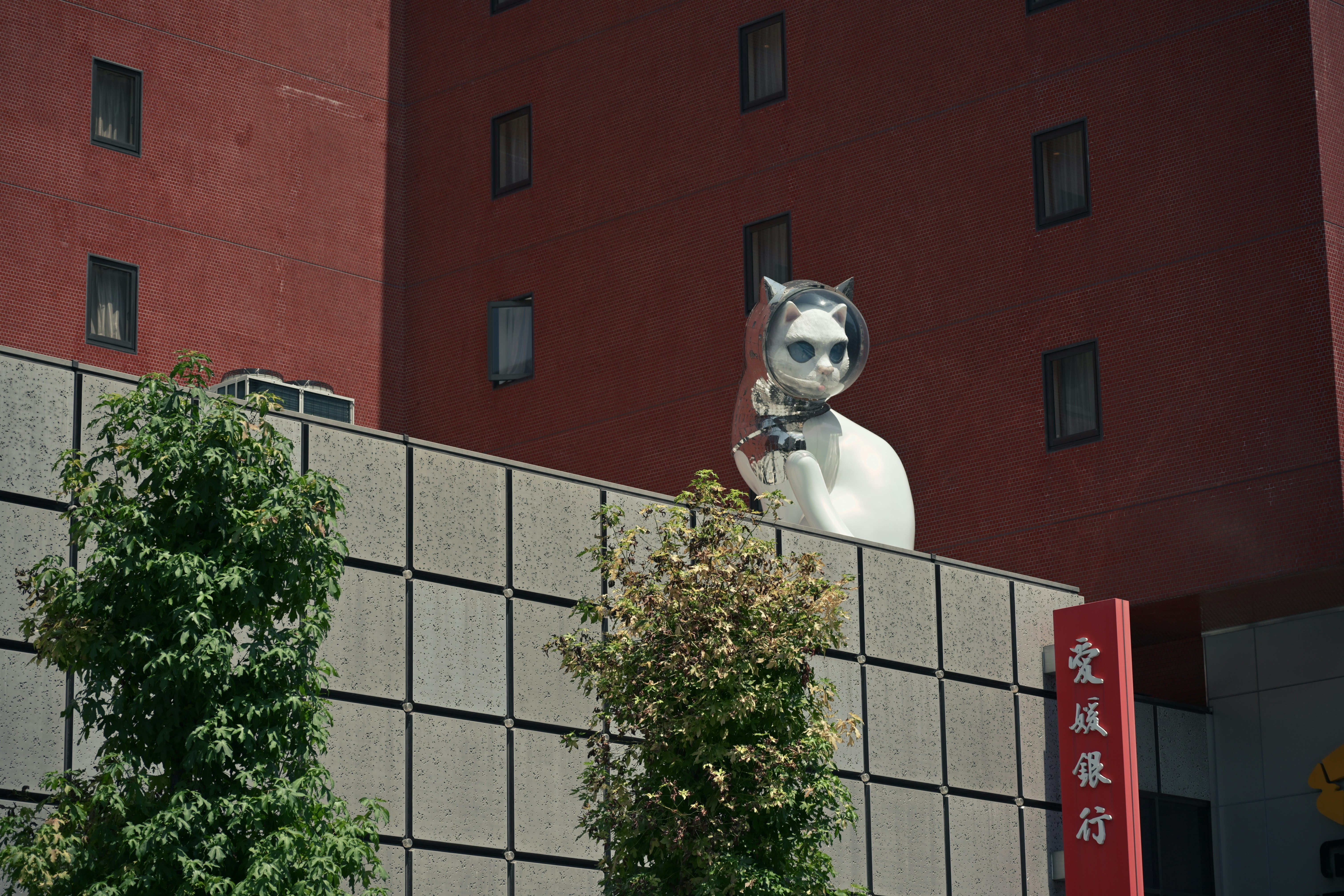 赤レンガの建物の壁に飾られた白い猫のオブジェ
