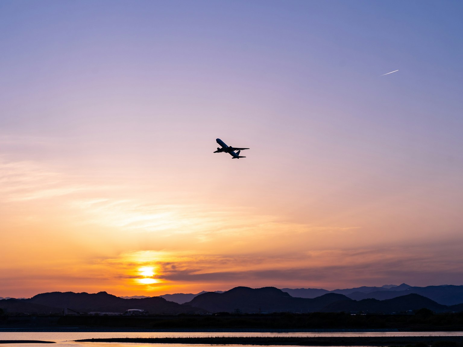 An airplane flying against a sunset sky