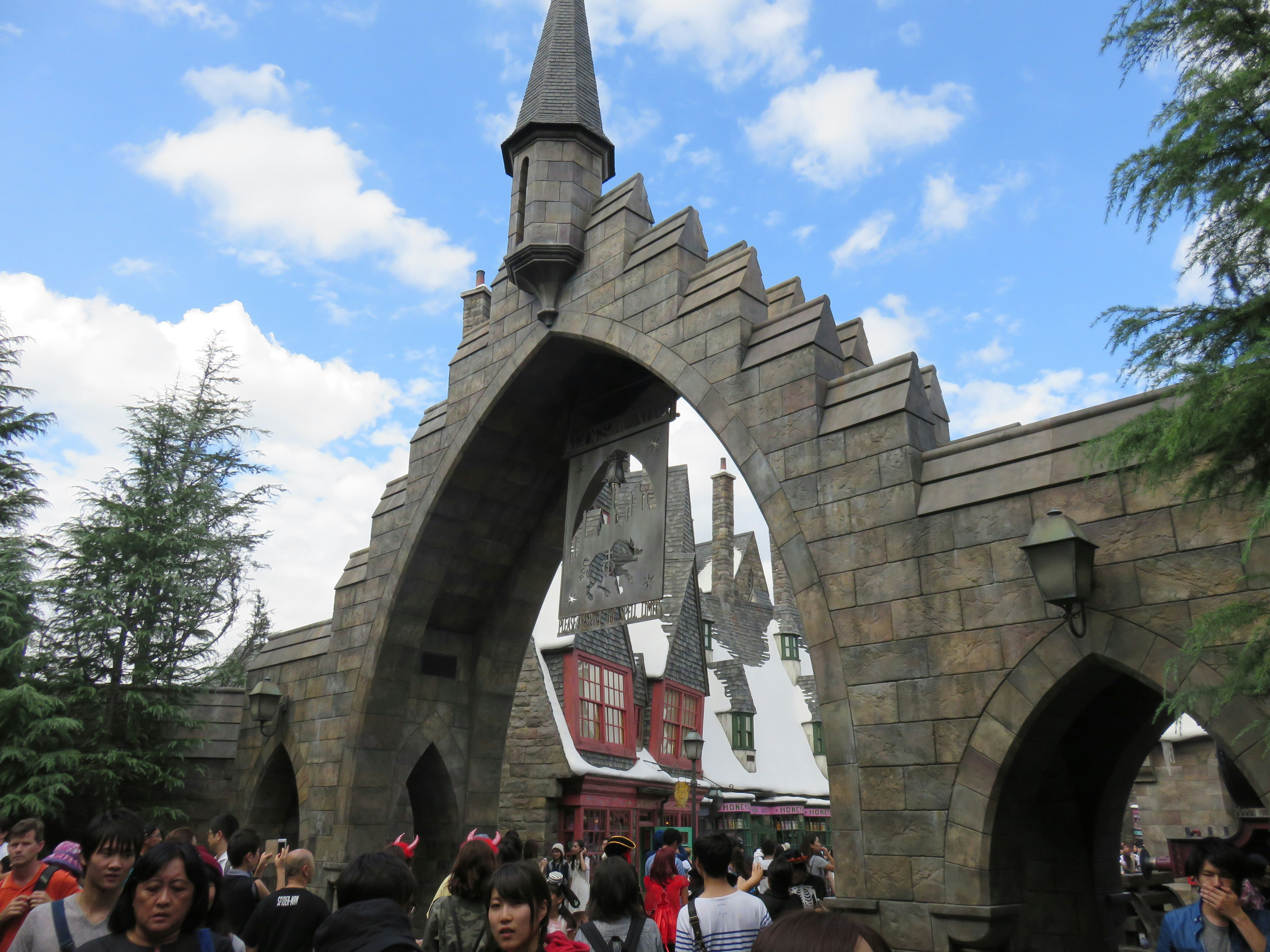 outdoor tourist area with a large stone arch and people walking