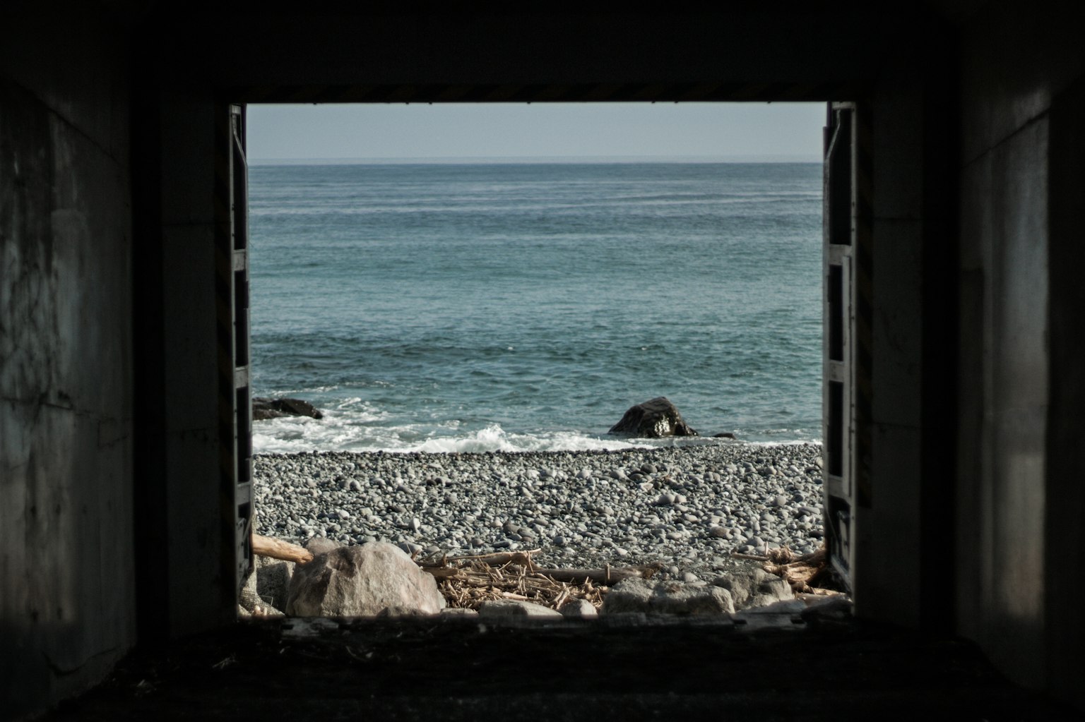 Vue de la plage rocheuse et de l'océan à travers l'ouverture d'un tunnel