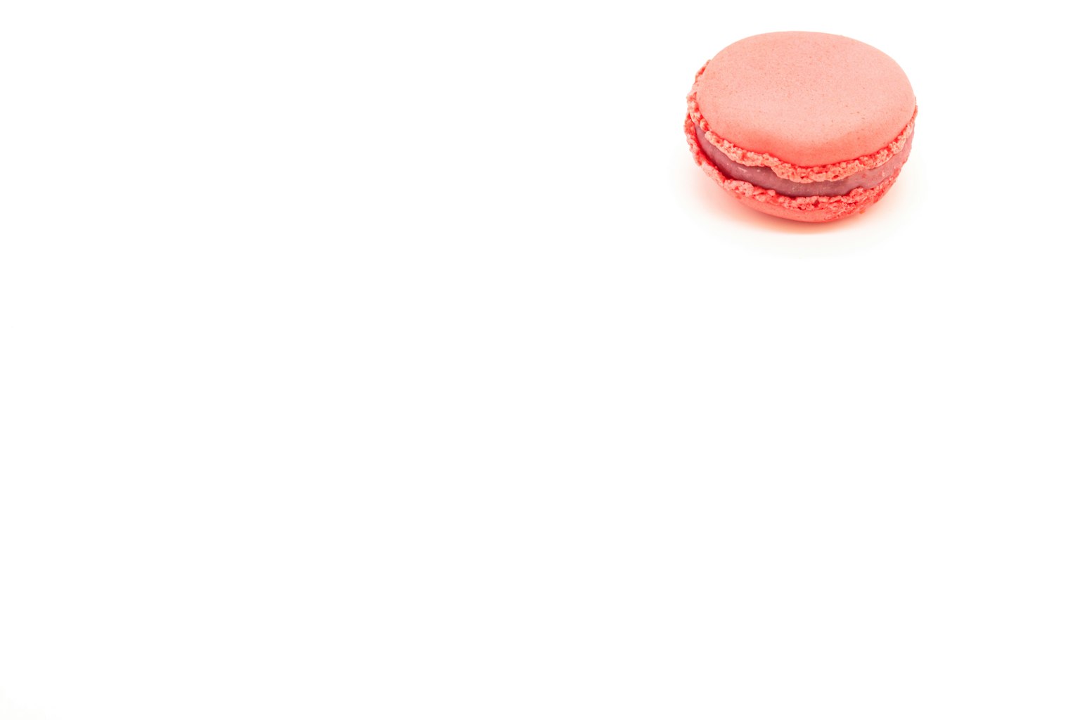 Một chiếc macaron hồng nhạt đặt trên nền trắng