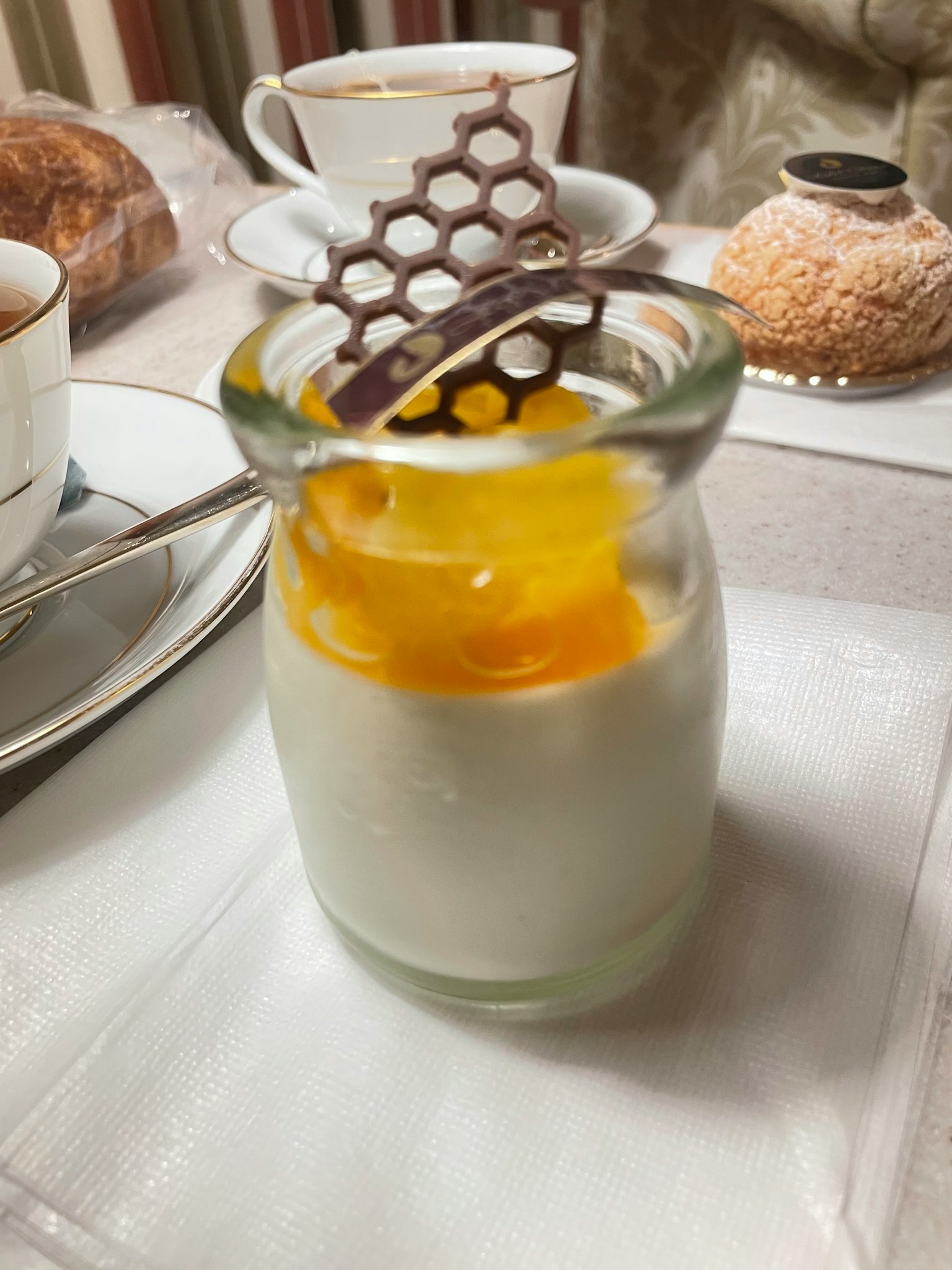 Dessert in einem kleinen Glasbehälter mit Mangosauce und Schokoladenhonigwaben-Dekoration