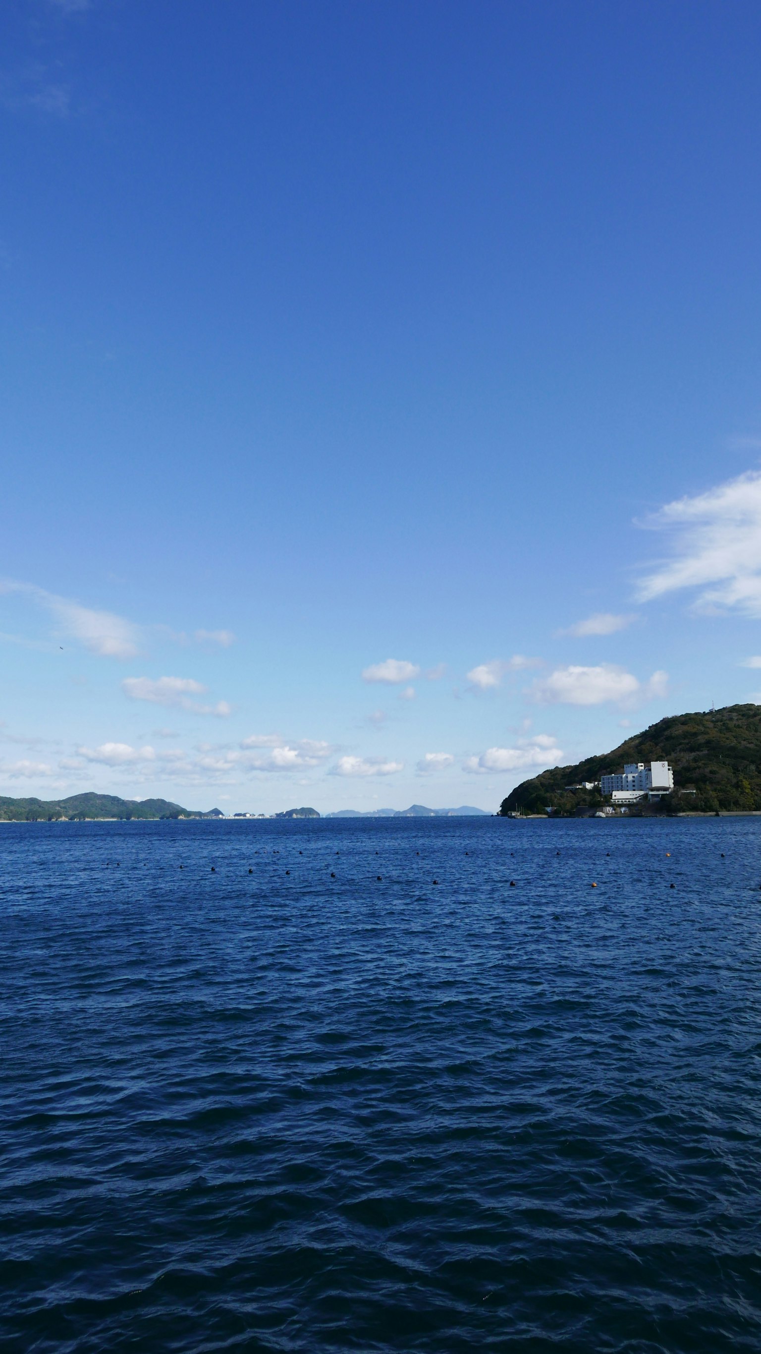 Pemandangan laut dan langit biru dengan pulau terlihat dan air tenang