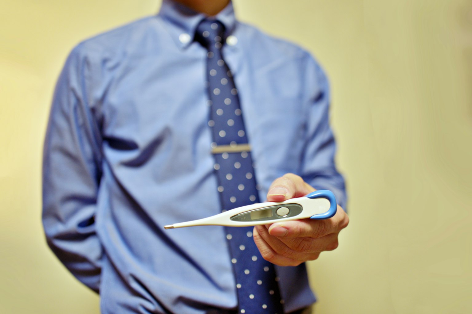Un homme en chemise bleue tenant un thermomètre