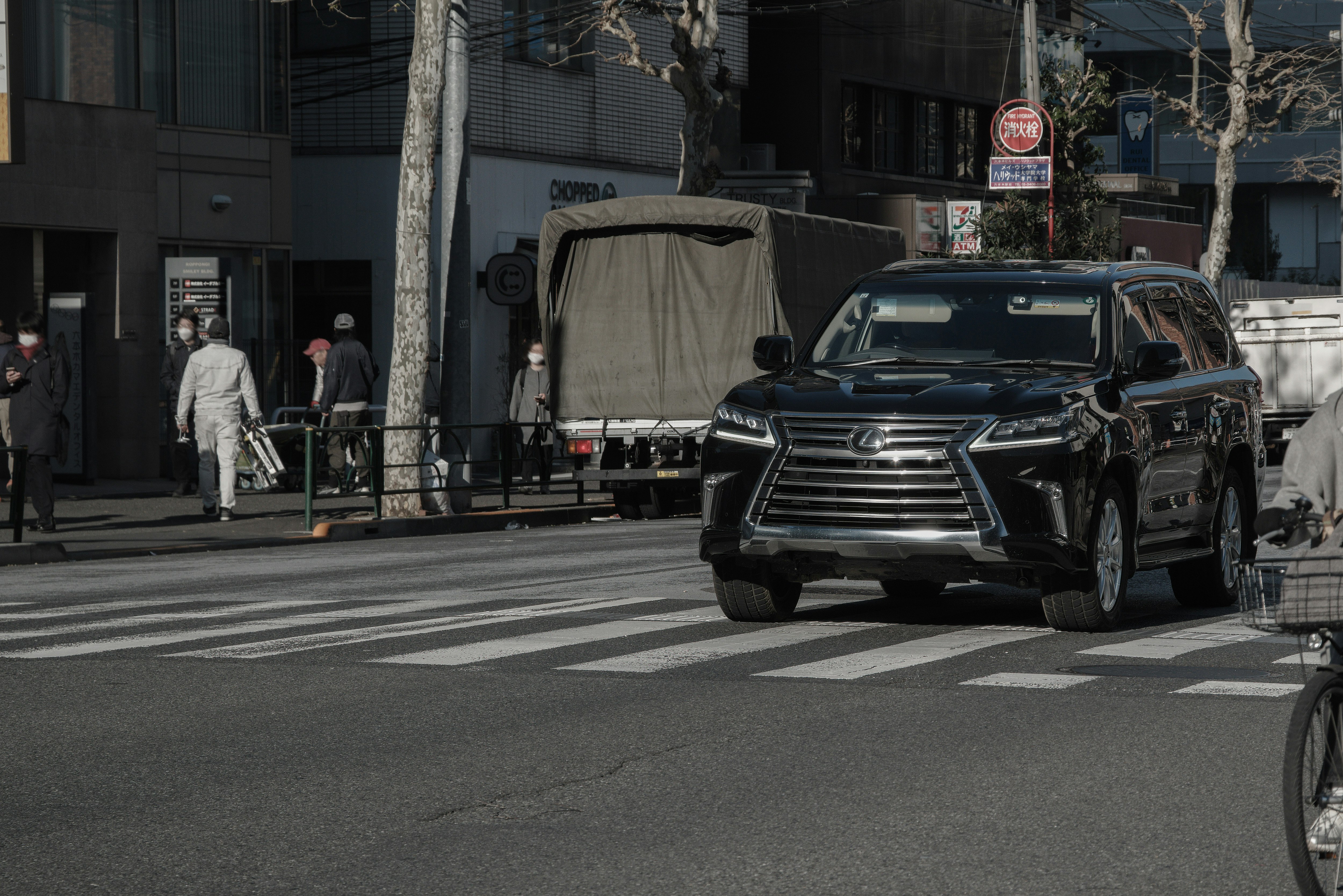 SUV negro circulando por una intersección urbana con peatones