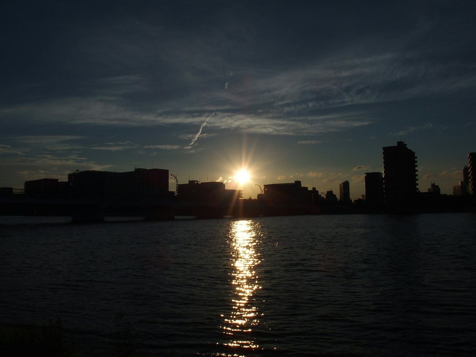 Silhouette de la ville contre un coucher de soleil se reflétant sur l'eau