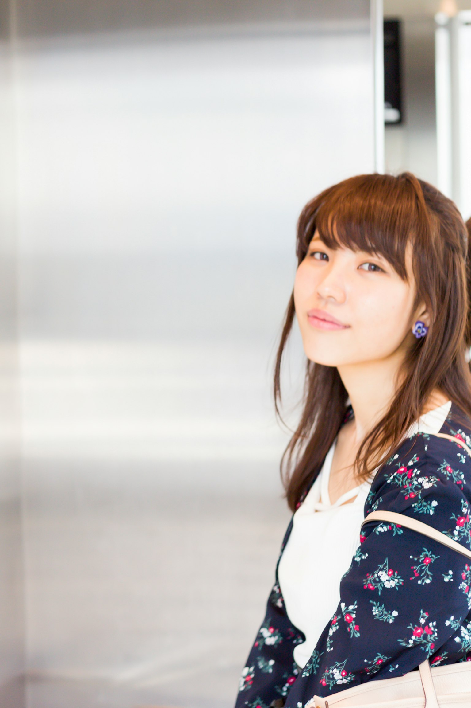 Retrato de una mujer cerca de un ascensor sonriendo con ropa de estampado floral