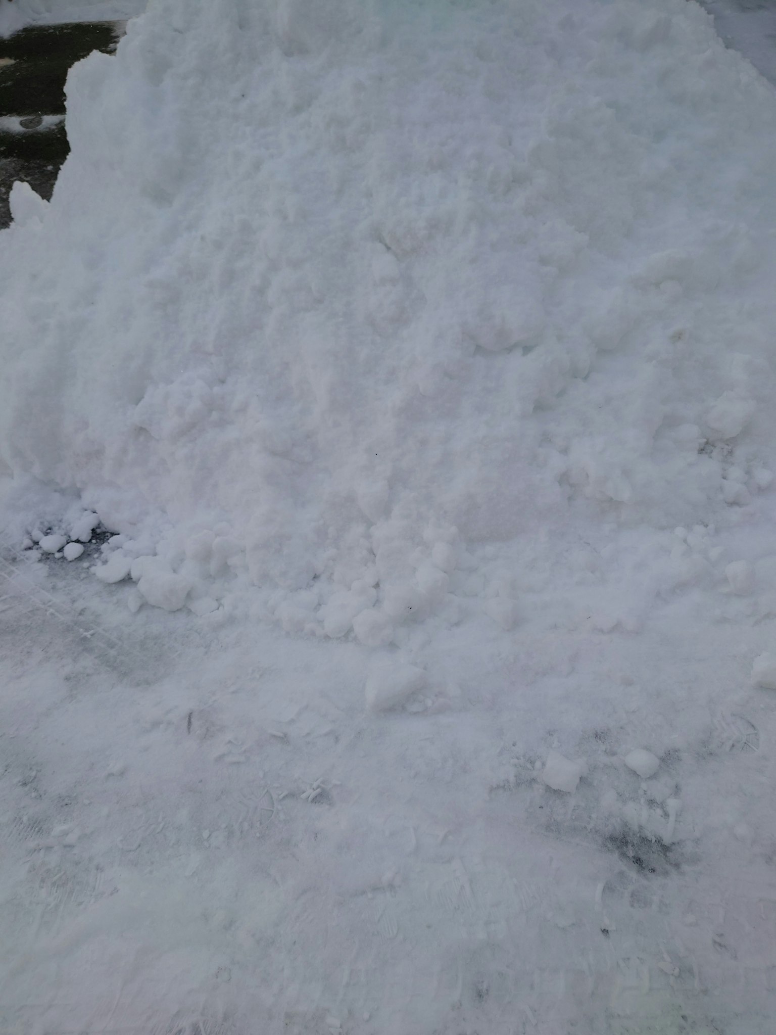 Un grande cumulo di neve con un terreno innevato