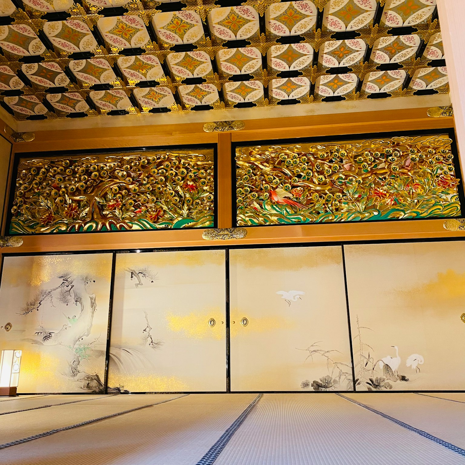 Traditional Japanese room interior with ornate gold paintings on walls and patterned ceiling