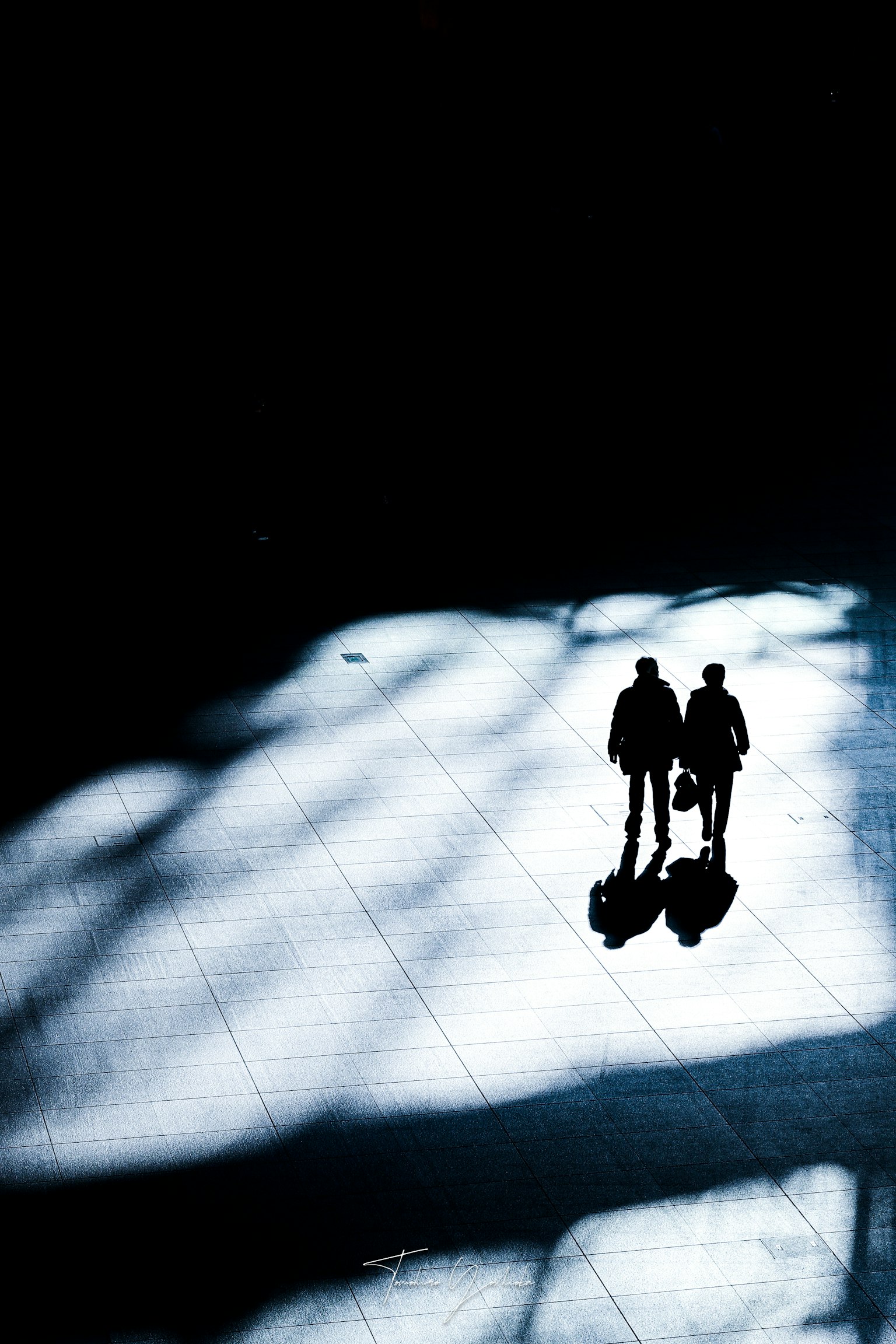 兩個人影在光與影的對比中行走