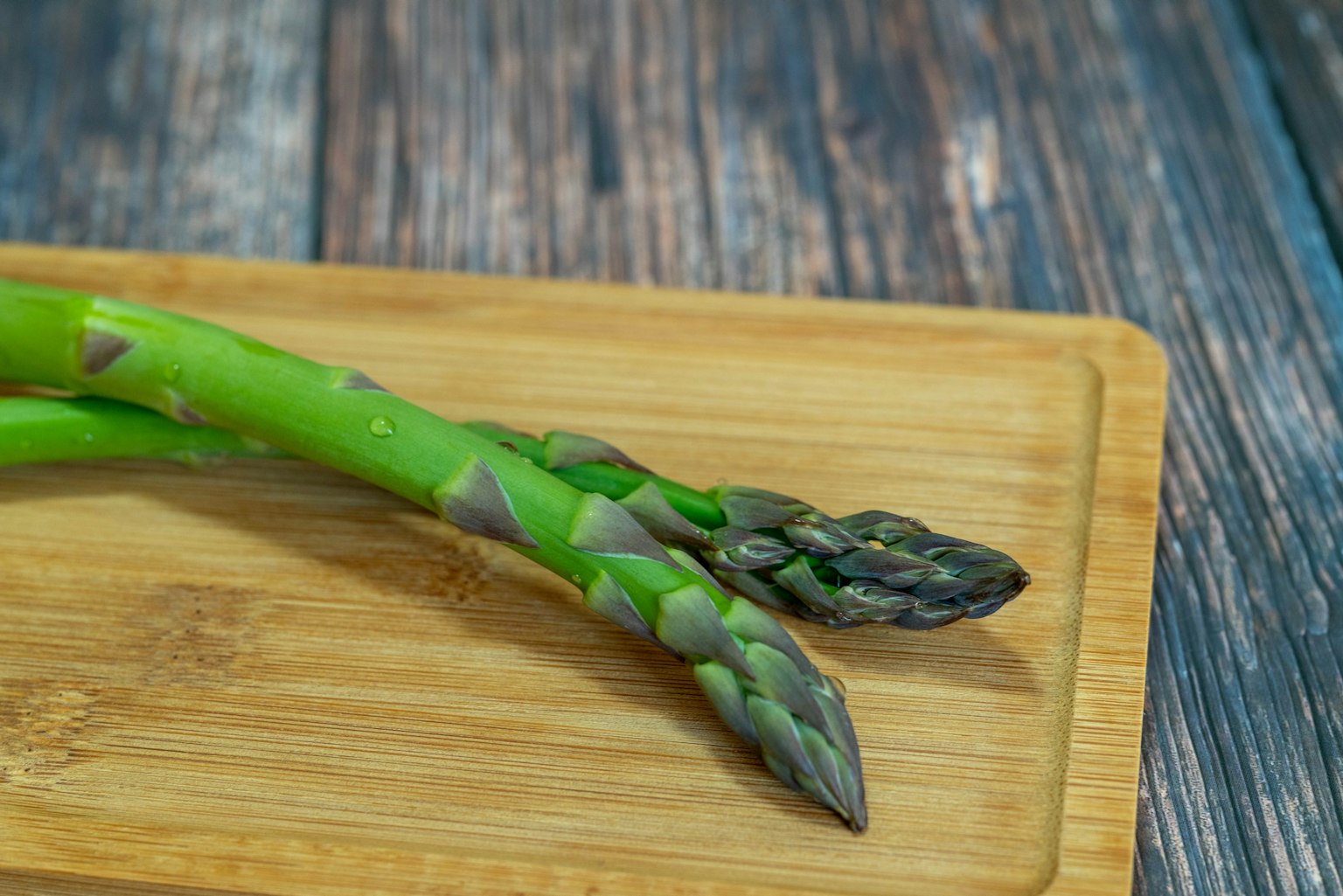 Asparagi verdi posati su un tagliere di legno