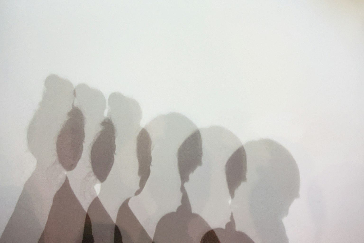Overlapping silhouettes of people against a light background