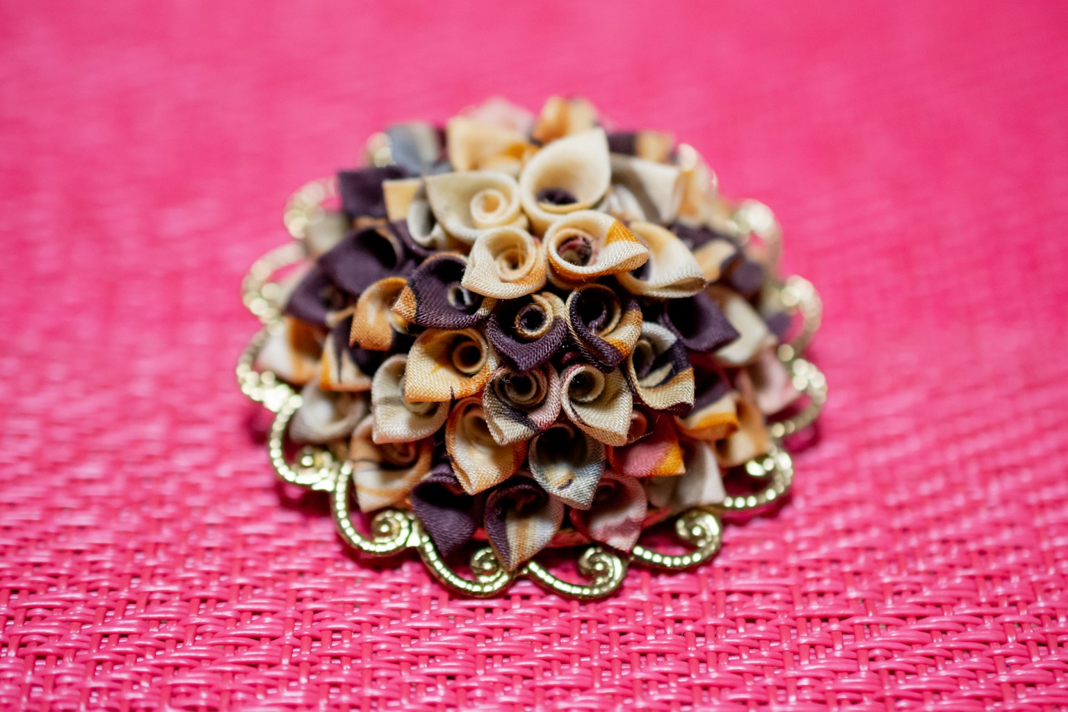 Une broche avec des décorations enroulées colorées sur un fond rose