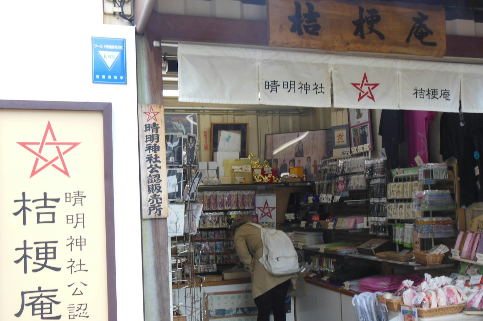 Fachada de una tienda de souvenirs frente a un santuario mostrando varios productos